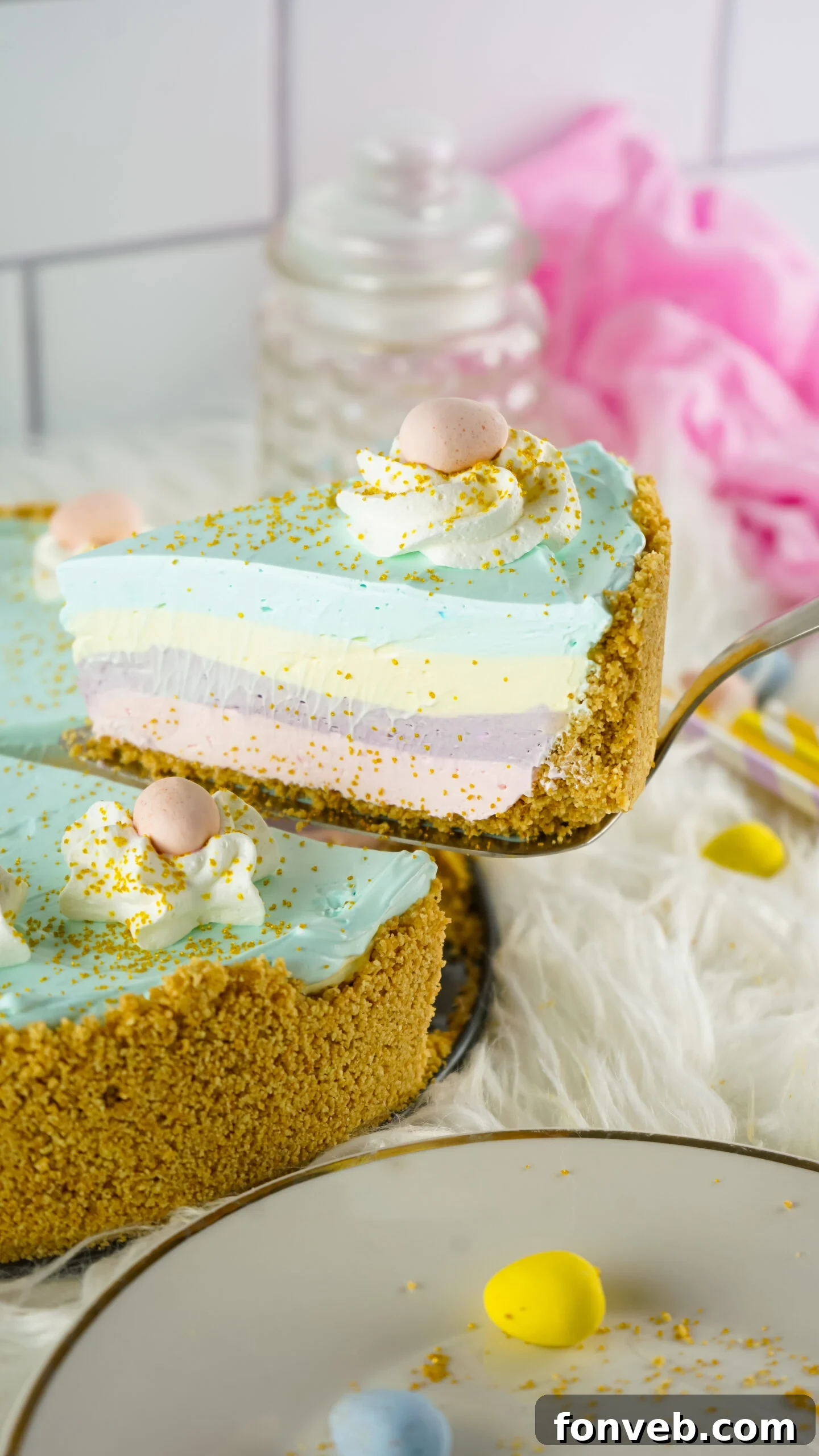 Zesty Easter Kool-Aid Pie 6 Close-up side view of a large Easter Kool Aid Pie with a slice being carefully lifted out by a silver pie server, revealing the vibrant layered structure.