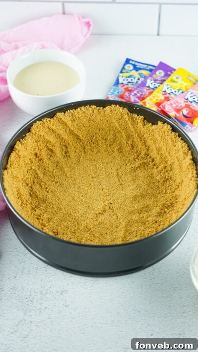 Zesty Easter Kool-Aid Pie 8 Hands carefully pressing graham cracker crust into a springform pan.