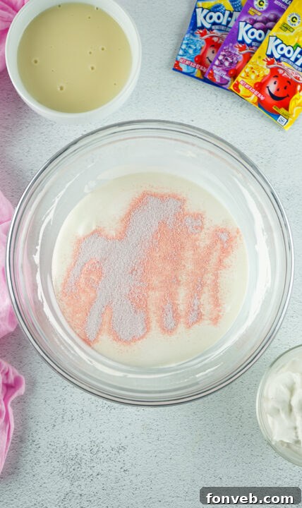 Zesty Easter Kool-Aid Pie 10 Spoon gently spreading the pink Kool-Aid layer evenly over the graham cracker crust in a springform pan.