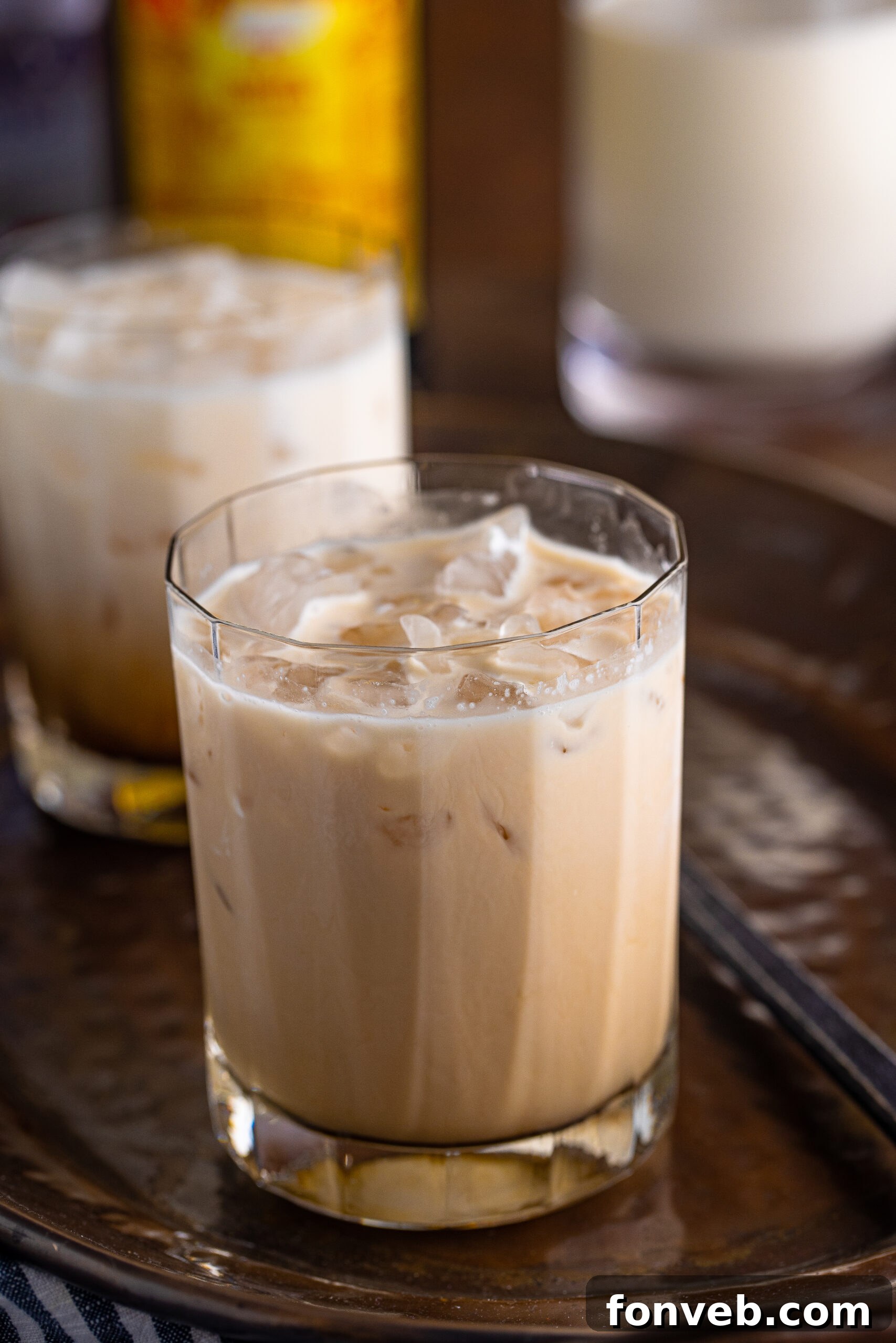 The Dude's Favorite Drink 2 A perfectly crafted White Russian in a clear glass, glistening with condensation, set against a dark, inviting background.