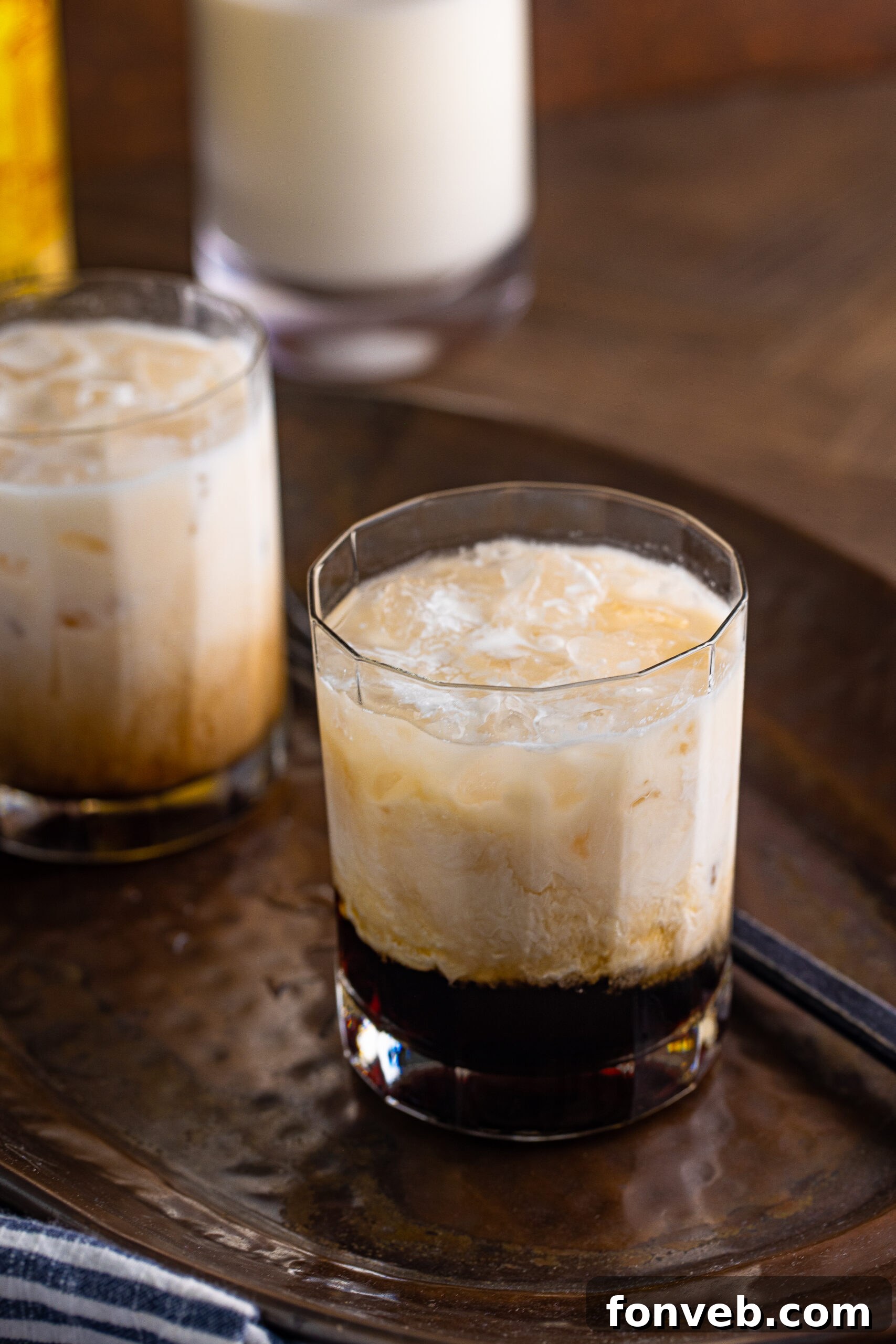 The Dude's Favorite Drink 11 A pristine White Russian cocktail in a clear glass, ready to be enjoyed, situated on a dark serving tray.