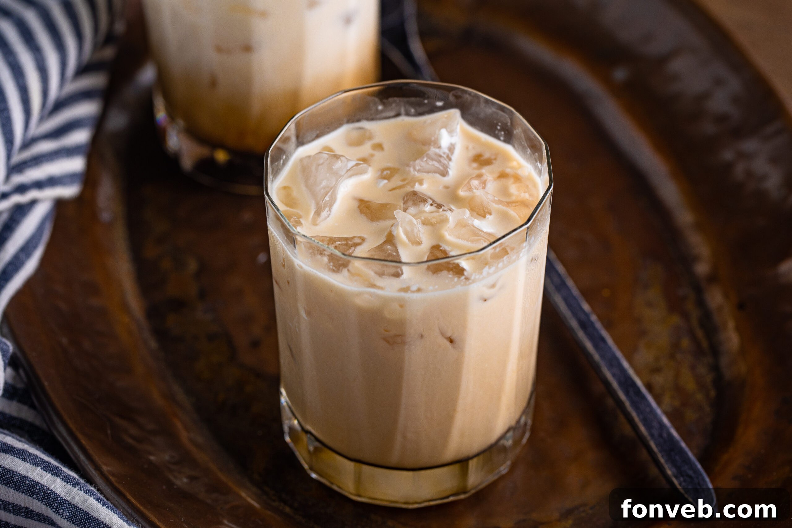 The Dude's Favorite Drink 4 Close-up of a White Russian cocktail in a glass, with the ingredients starting to meld, resting on a dark, textured surface.