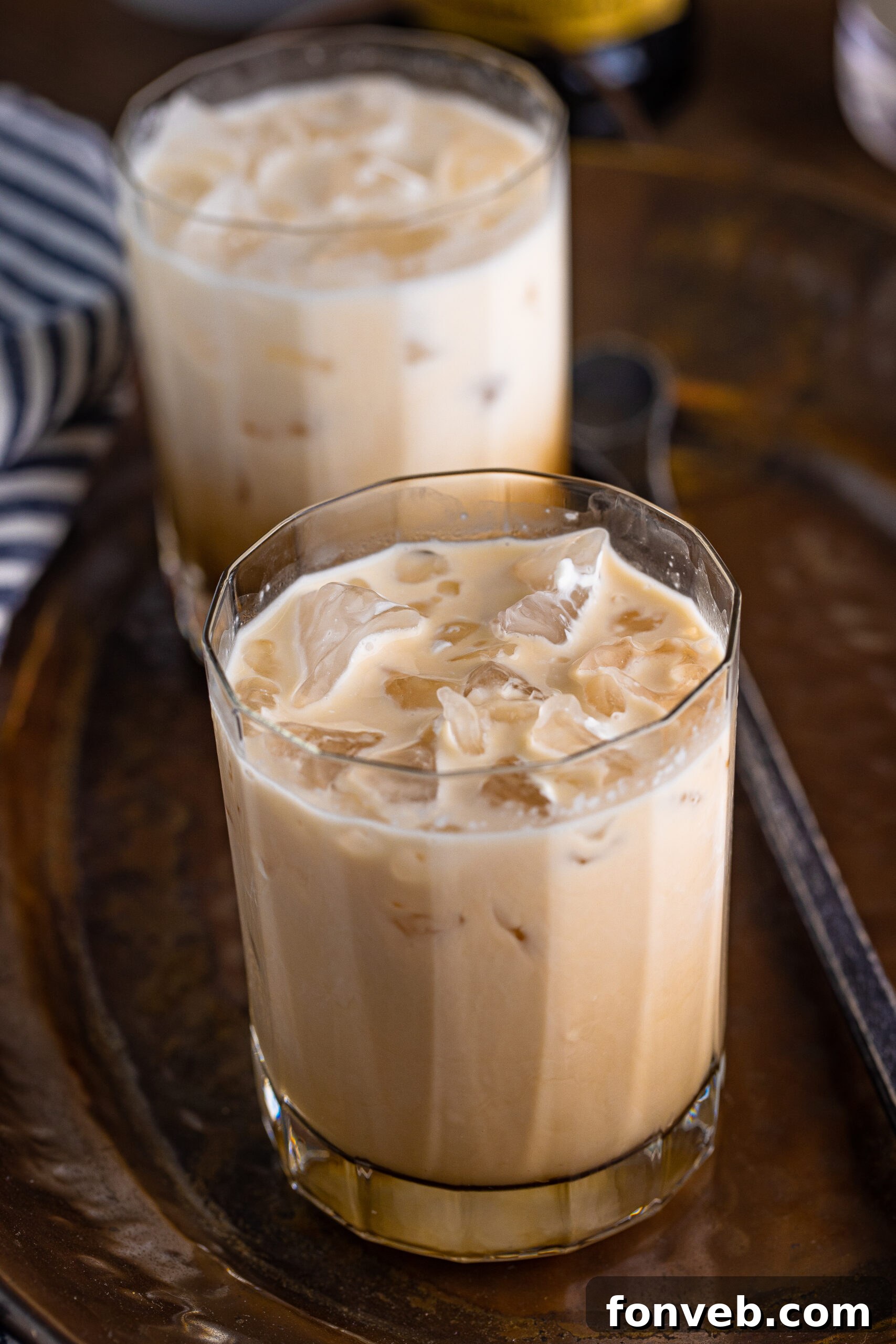 The Dude's Favorite Drink 5 A clear glass filled with a creamy White Russian, showcasing its rich texture and depth, on a dark serving tray.