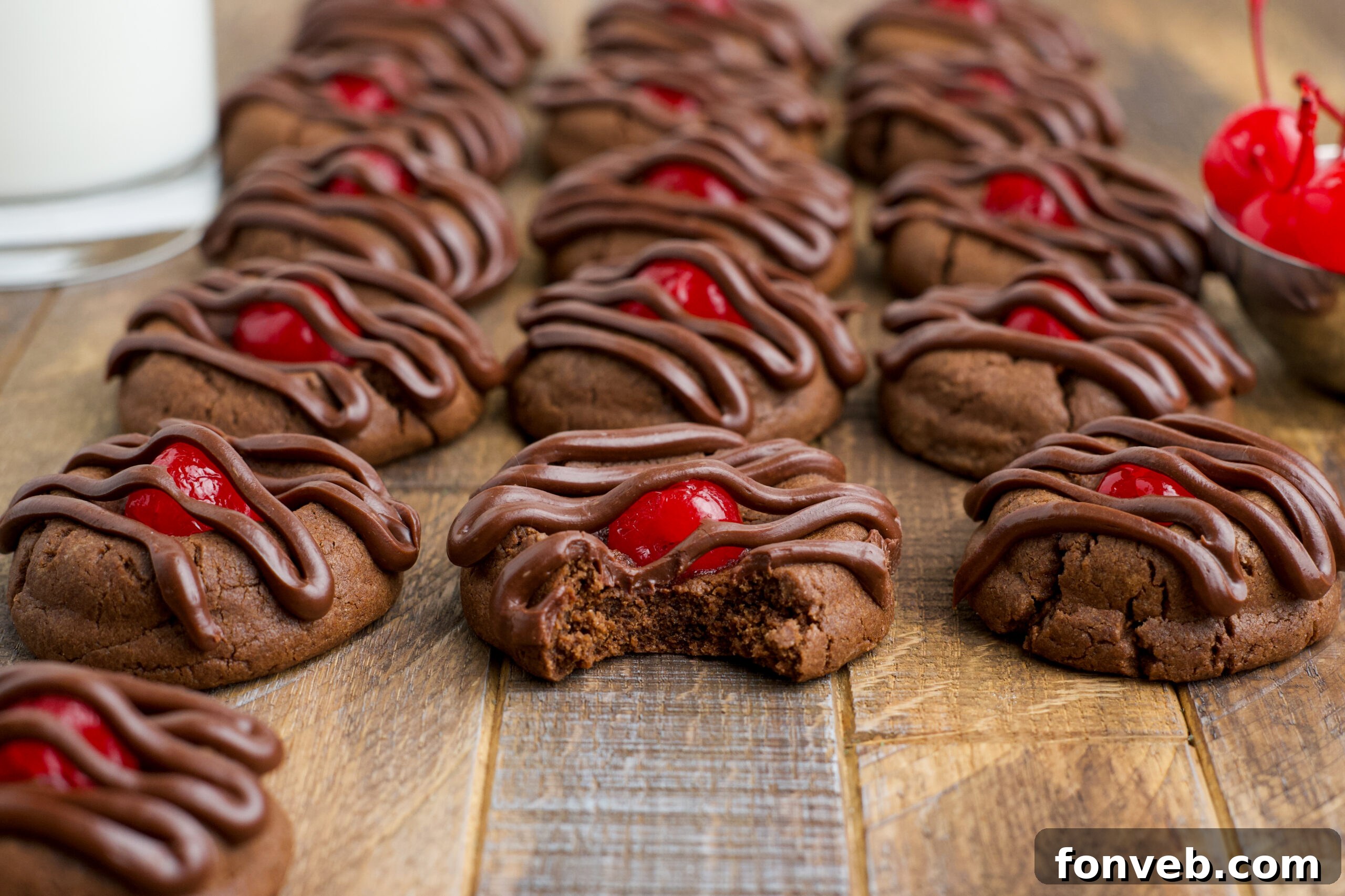 Chocolate Cherry Cookies on a wooden table with the front one missing a bite