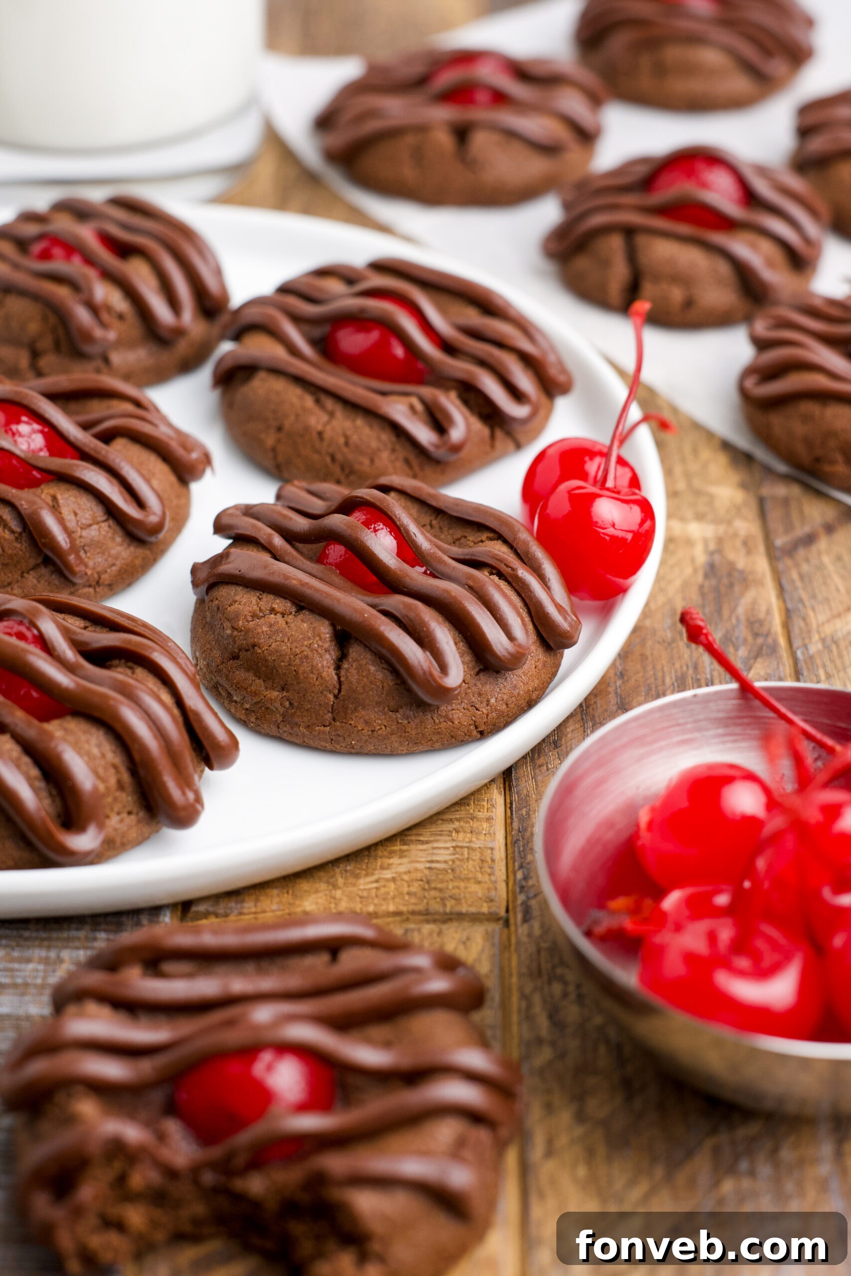 Chocolate Cherry Cookies on a white plate with maraschino cherries in the background.