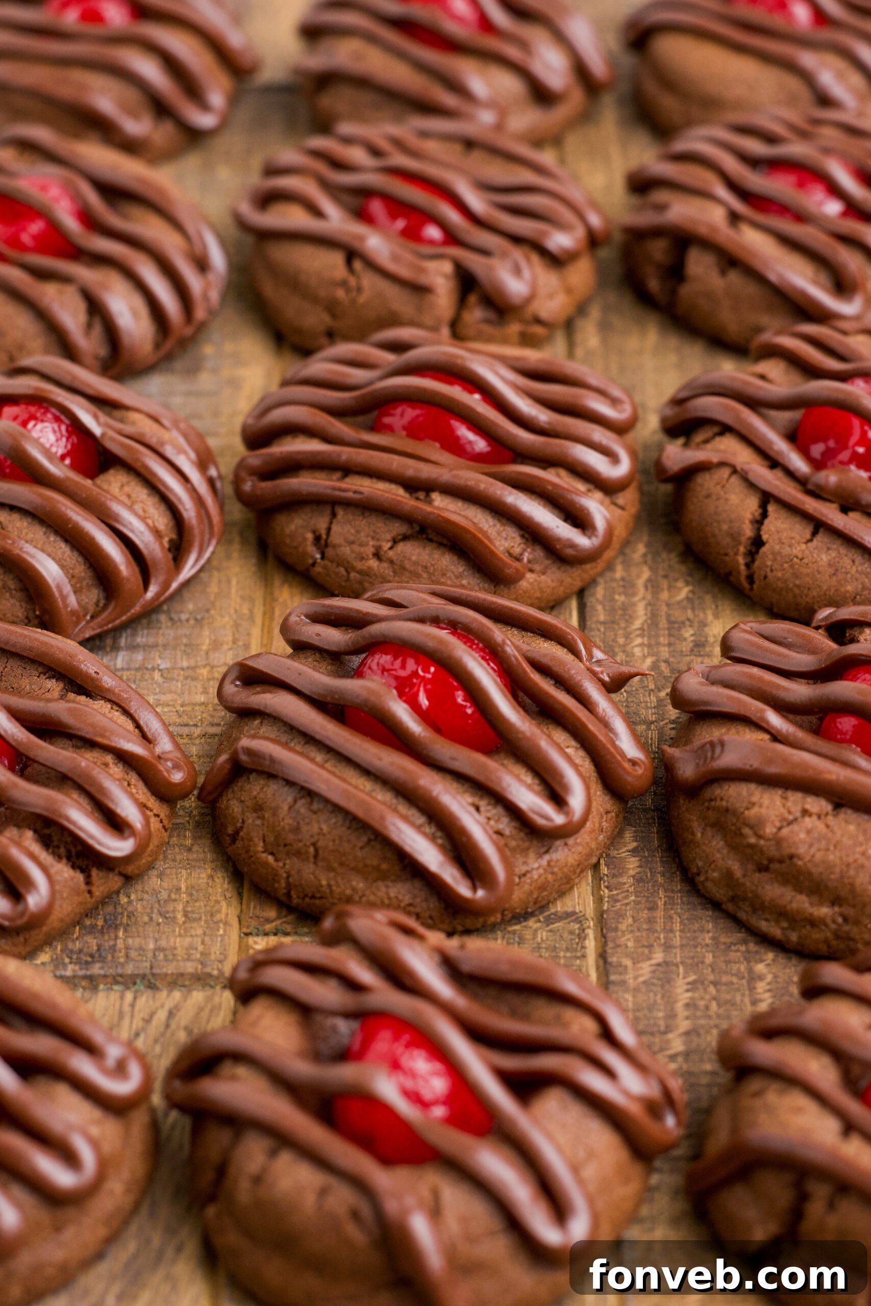 Chocolate Cherry Cookies lined up on a dark wood background.