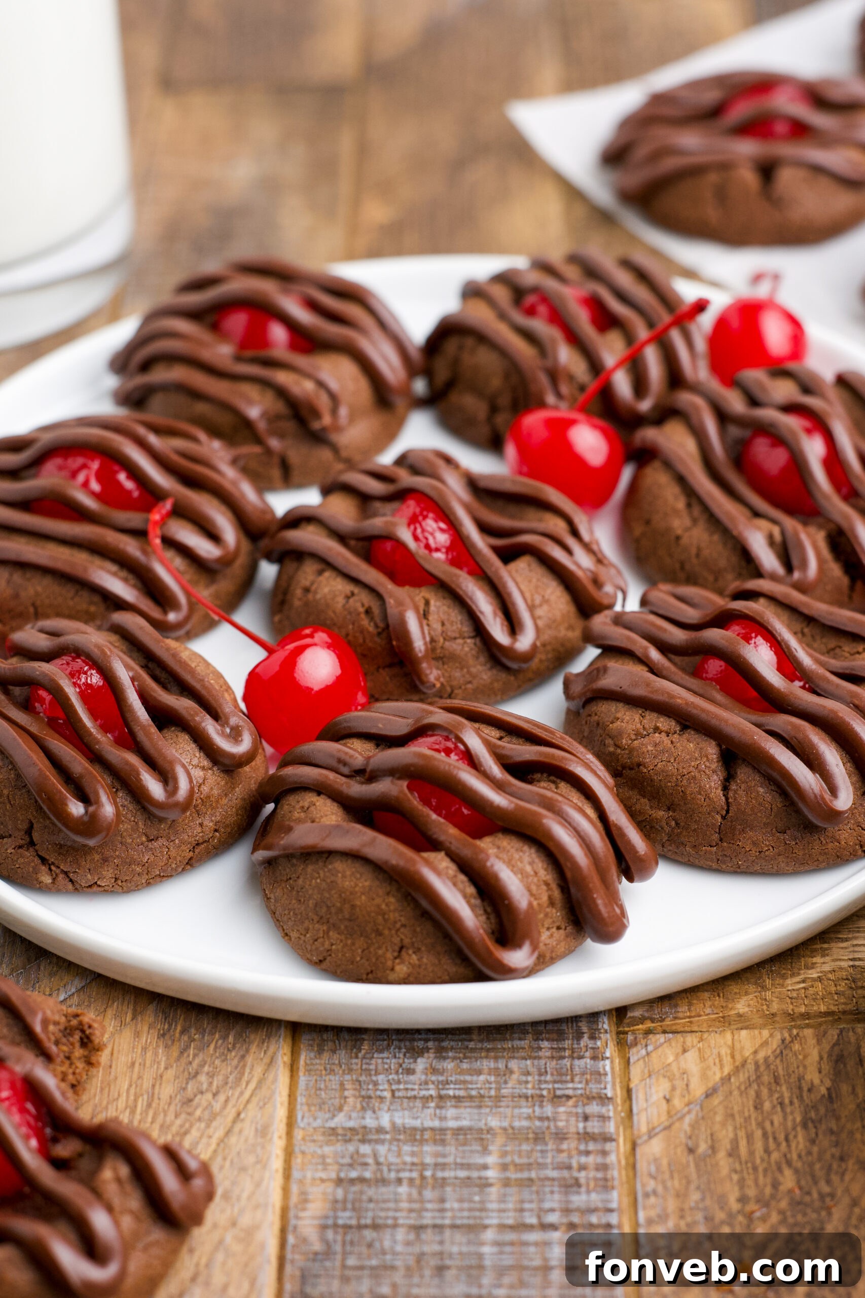 Chocolate Cherry Cookies on a white plate with maraschino cherries in the background.