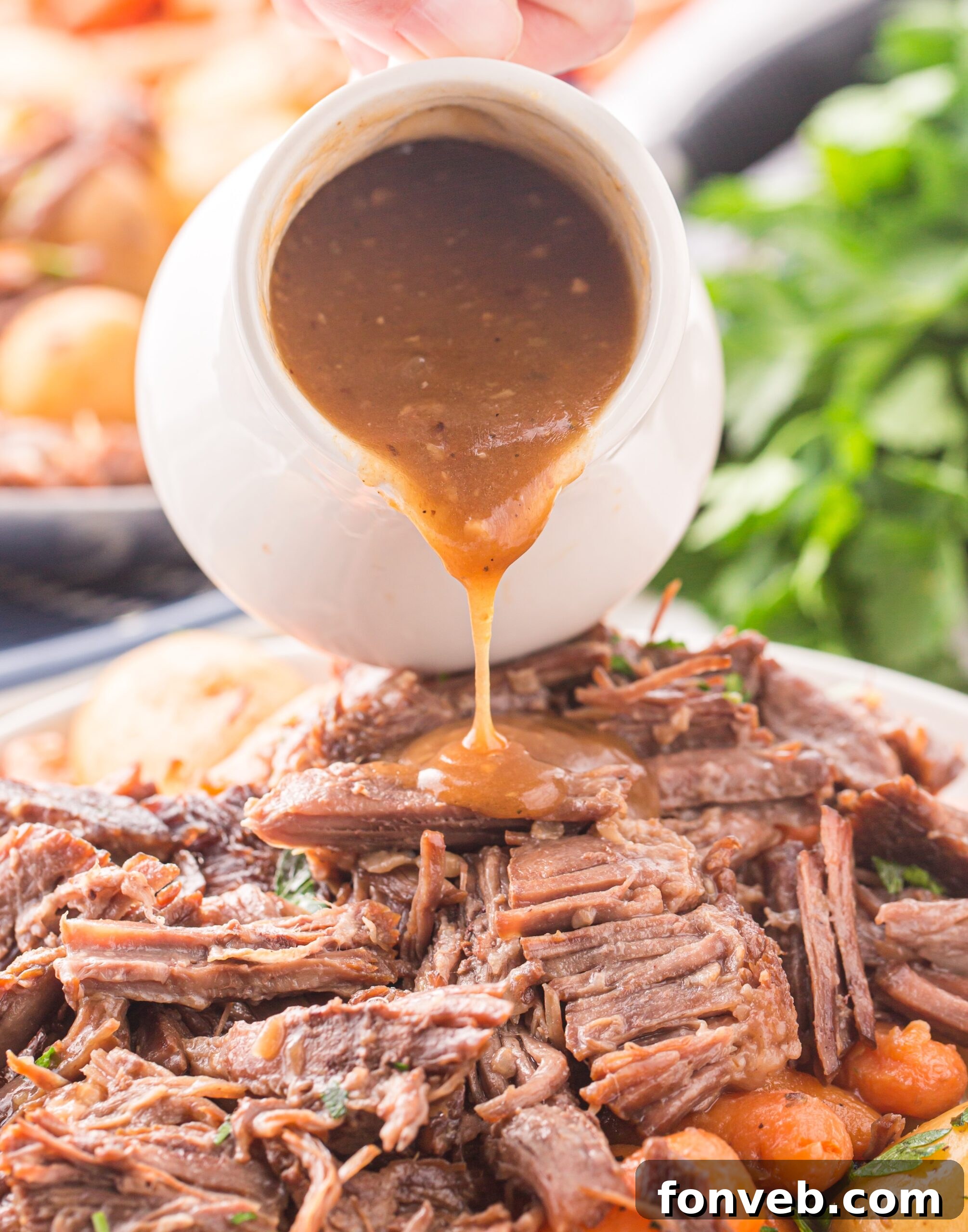 Melt-in-Your-Mouth Instant Pot Pot Roast 7 Pouring gravy from a white gravy boat onto the pot roast.