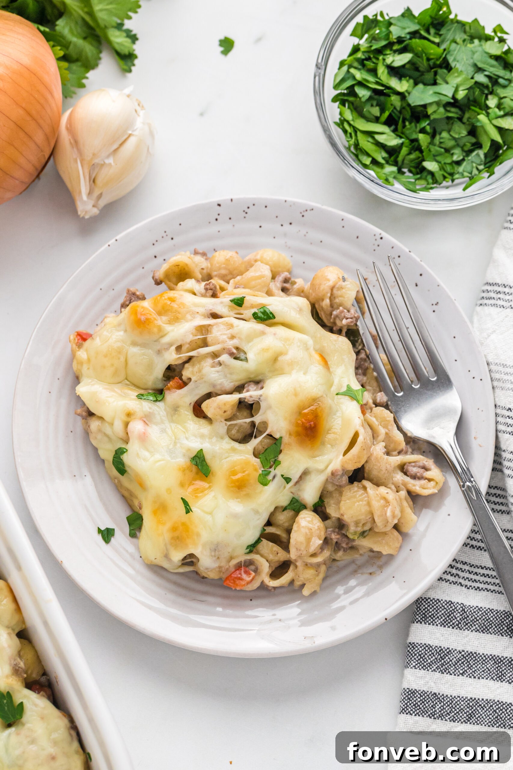 Overhead view of Philly Cheesesteak Casserole on a white dish served with a silver fork.