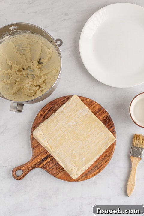 Step-by-step image of folding the bottom corner of the egg roll wrapper over the filling.