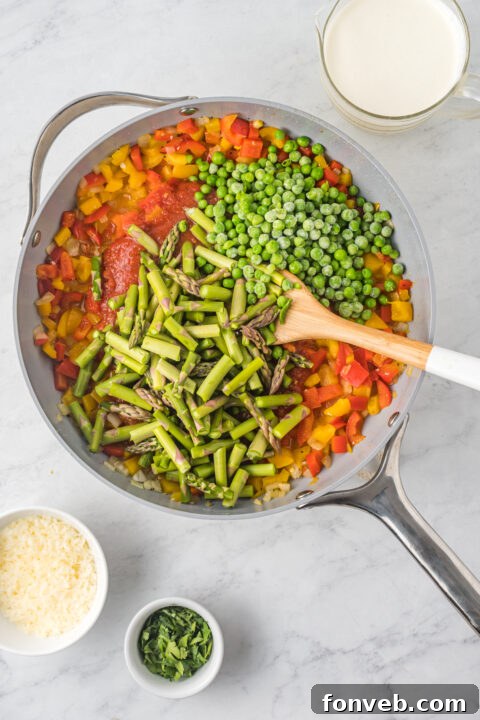 Cooked penne pasta being added to the simmering Cajun sauce in the pan.
