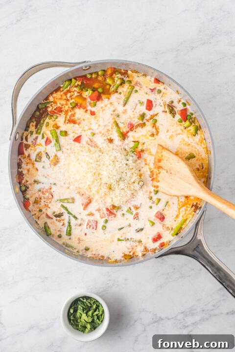The cooked chicken being added back into the pasta and sauce mixture.
