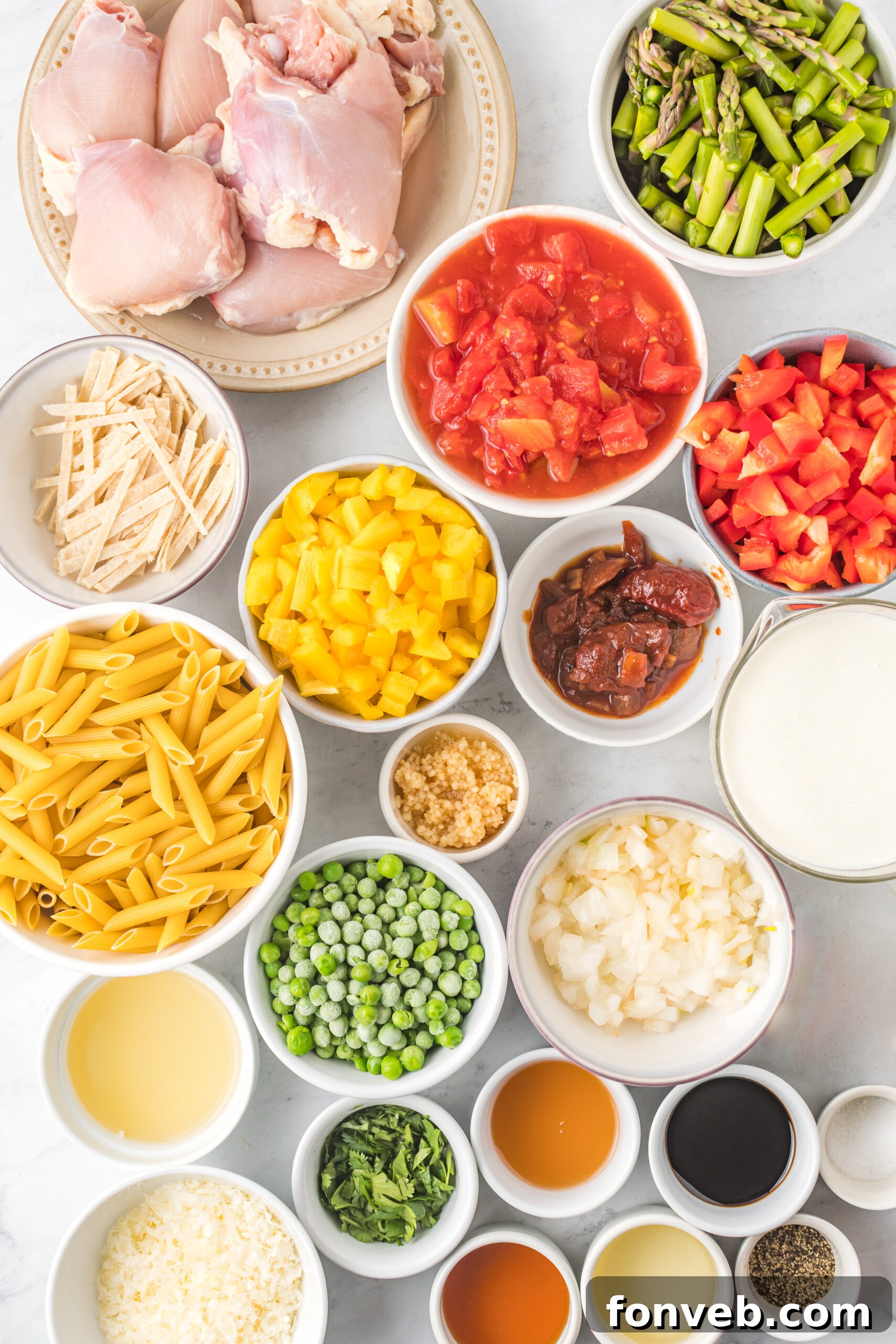 An organized array of ingredients for Cajun Chicken Pasta, including fresh vegetables, chicken, pasta, and spices.