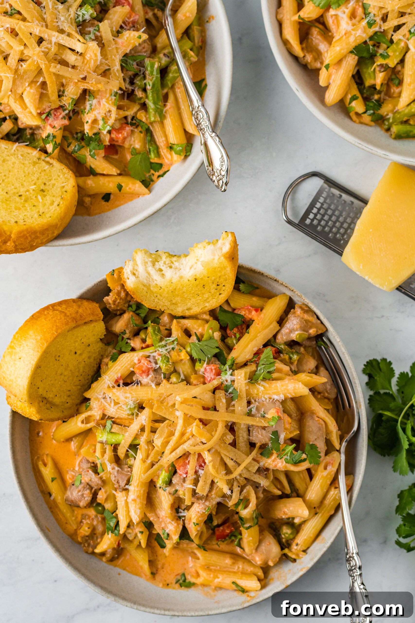 A beautifully presented dish of Cajun Chicken Pasta, garnished and ready to serve, with garlic bread in the background.