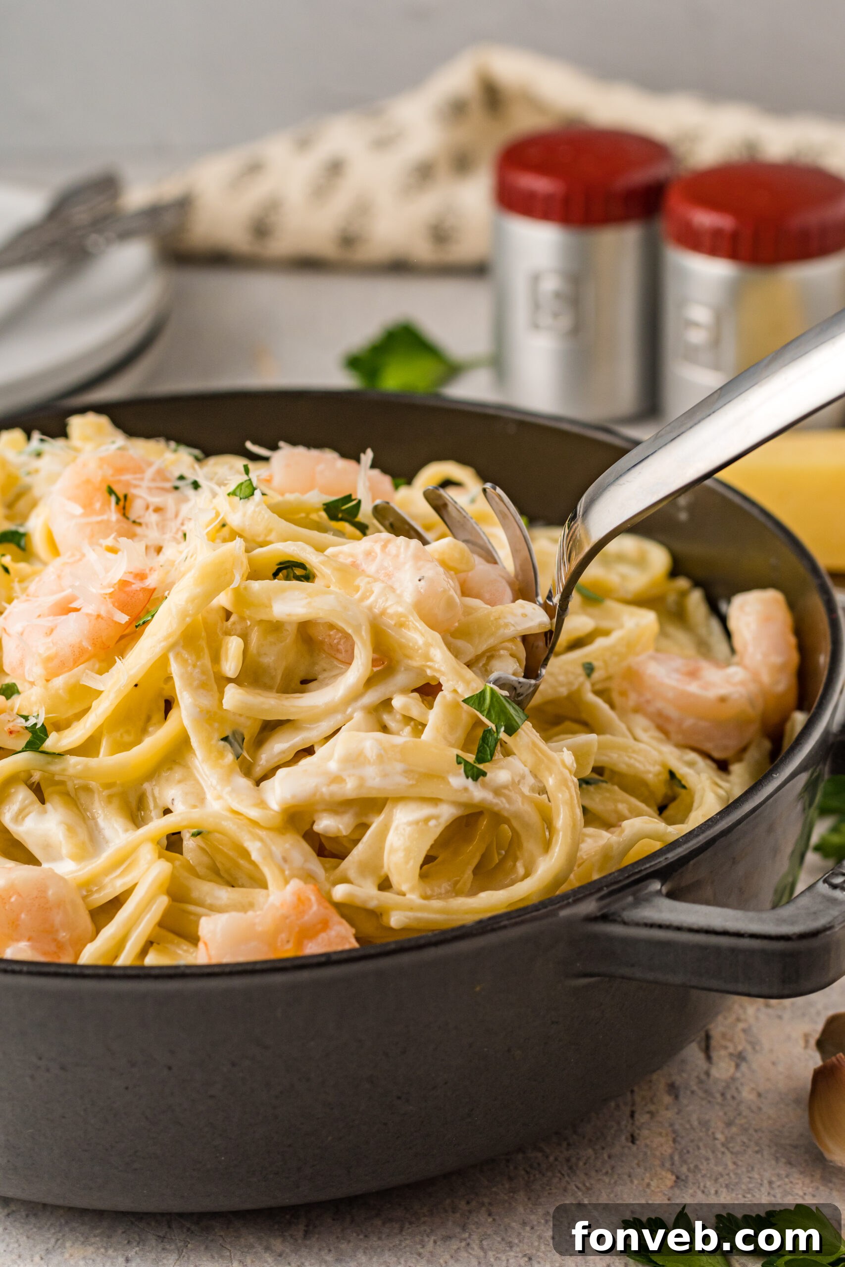 Front view of a silver serving spoon scooping out Shrimp Alfredo.