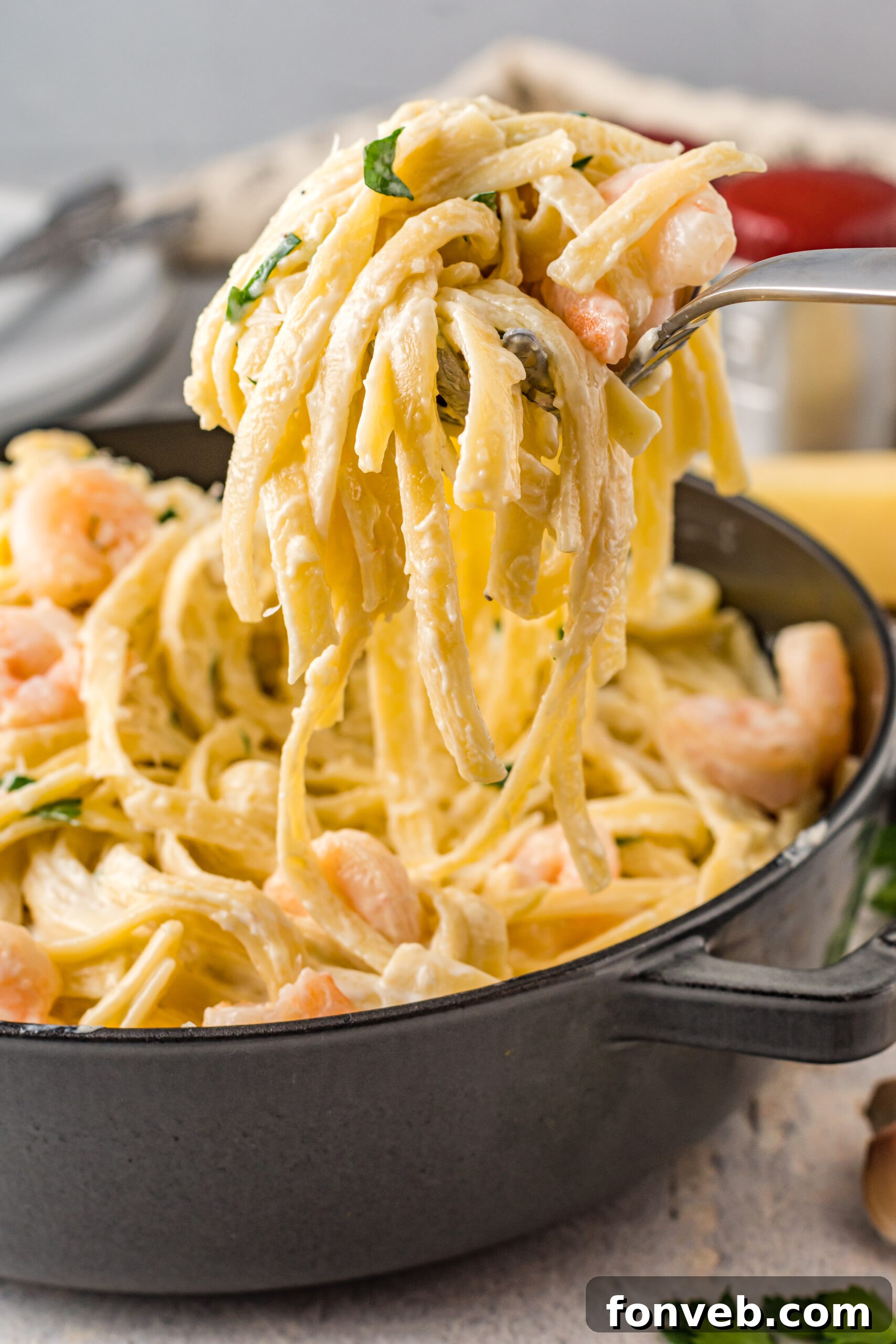 Front view of a silver serving spoon scooping out Shrimp Alfredo.