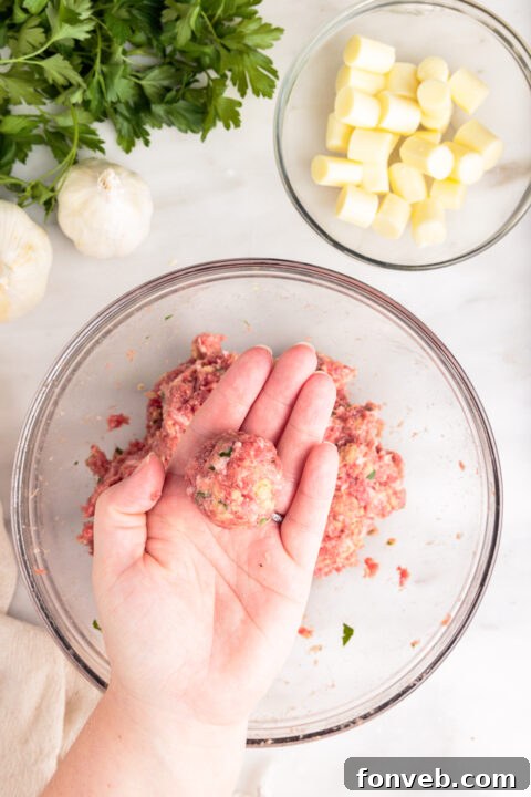 A perfectly formed, raw mozzarella stuffed meatball, ready for baking.