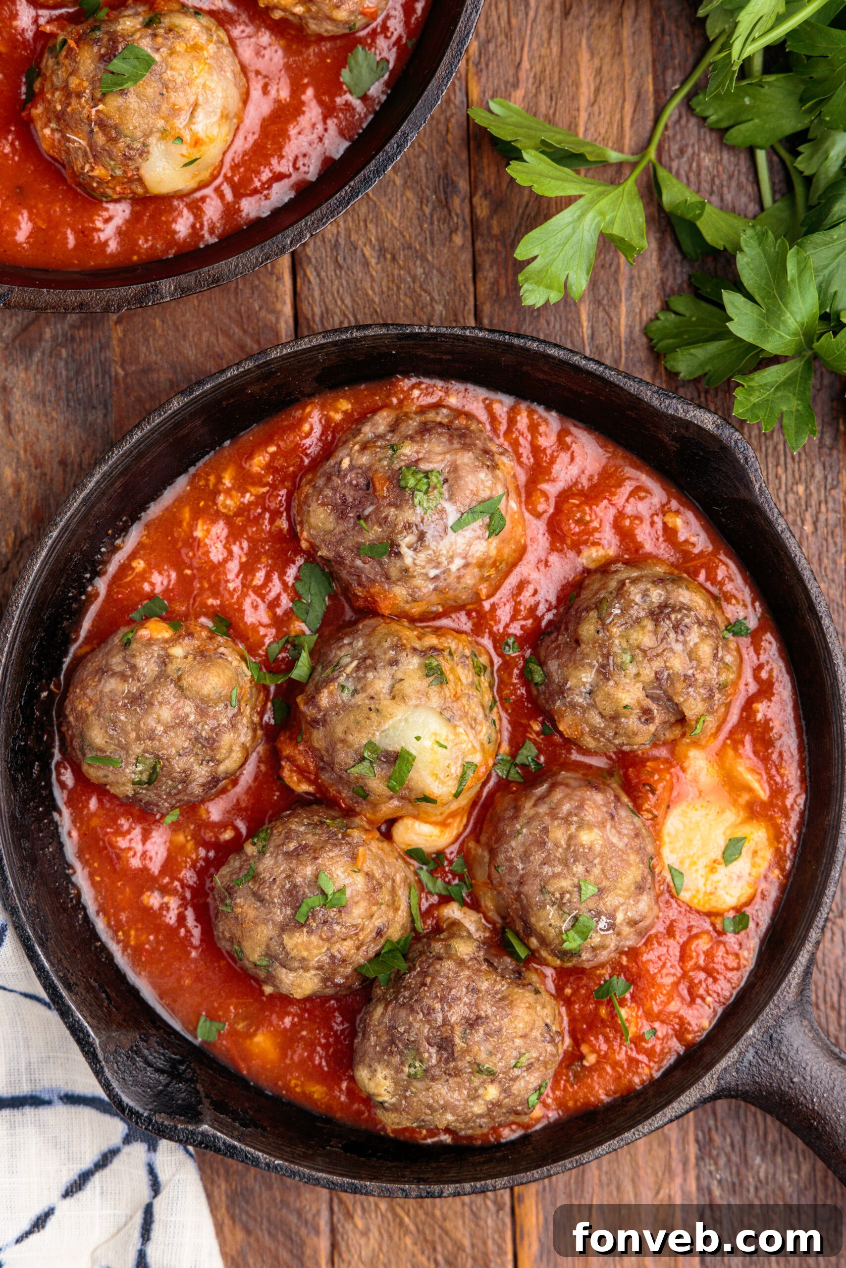 Close-up overhead view of golden-brown Mozzarella Stuffed Meatballs in a black cast iron skillet.