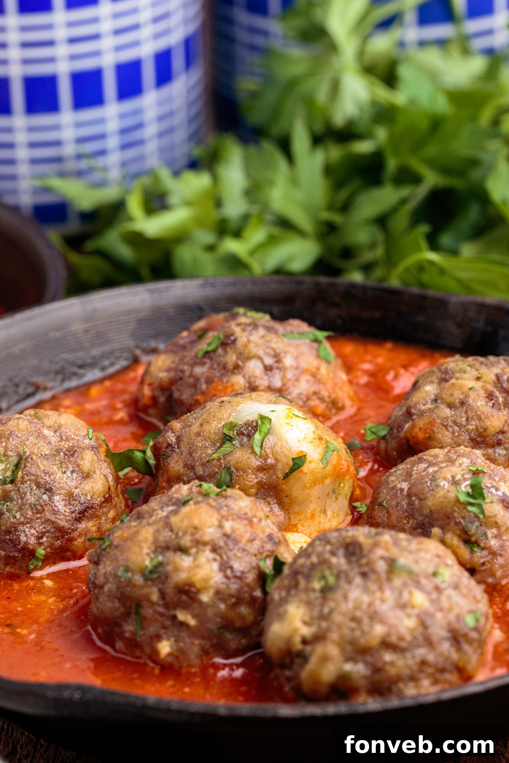 Side view of perfectly cooked Mozzarella Stuffed Meatballs, some with visible melted cheese, resting in a cast iron skillet.