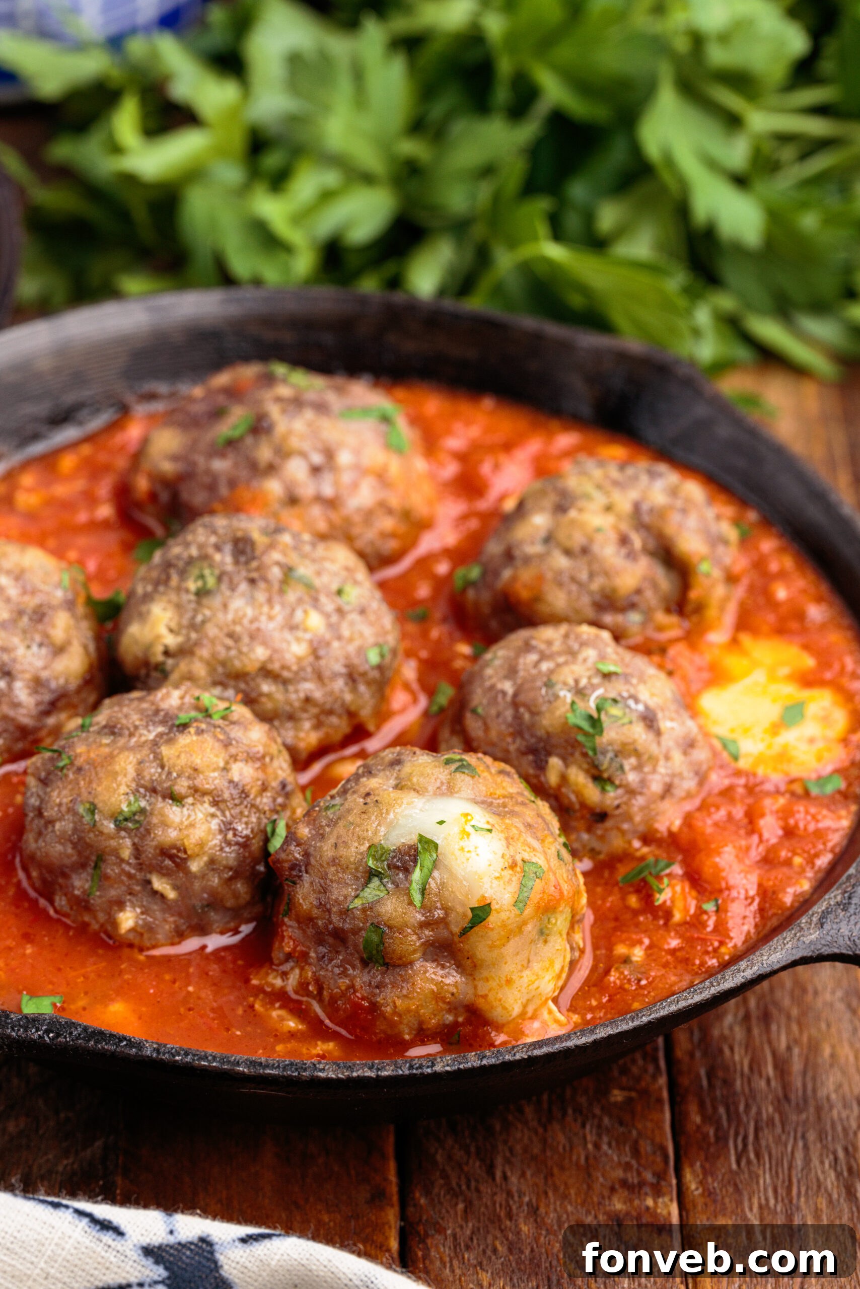 Side view of several Mozzarella Stuffed Meatballs in a dark cast iron skillet, showcasing their round, uniform shape.