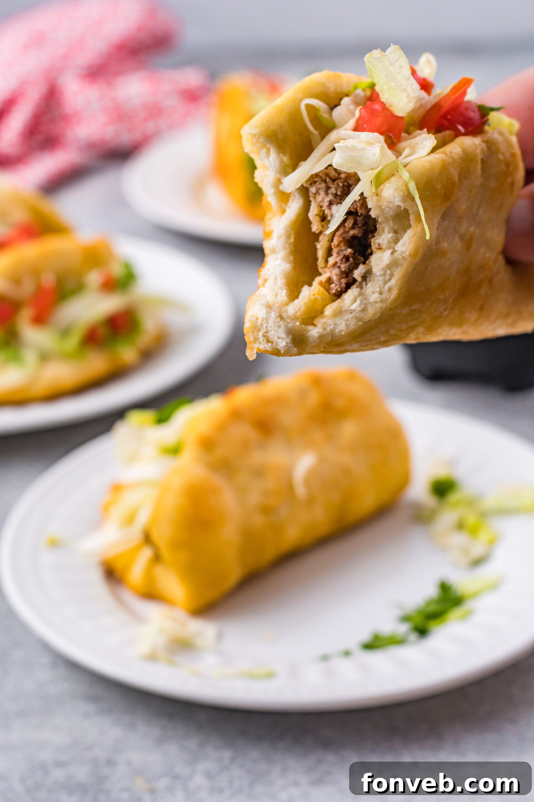 Front view of a homemade Taco Bell Chalupa being held, with a bite taken out, revealing the layers of filling.