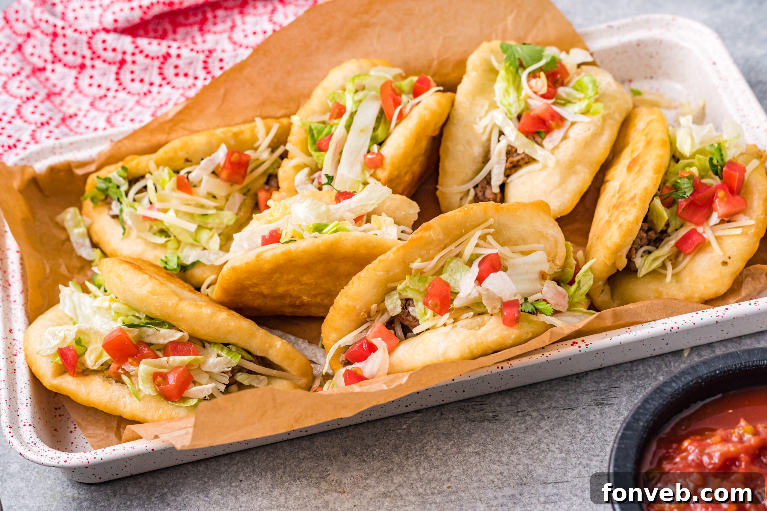 View of Taco Bell Chalupas freshly prepared and arranged in a serving tray lined with parchment paper, making them easy to pick up and enjoy.