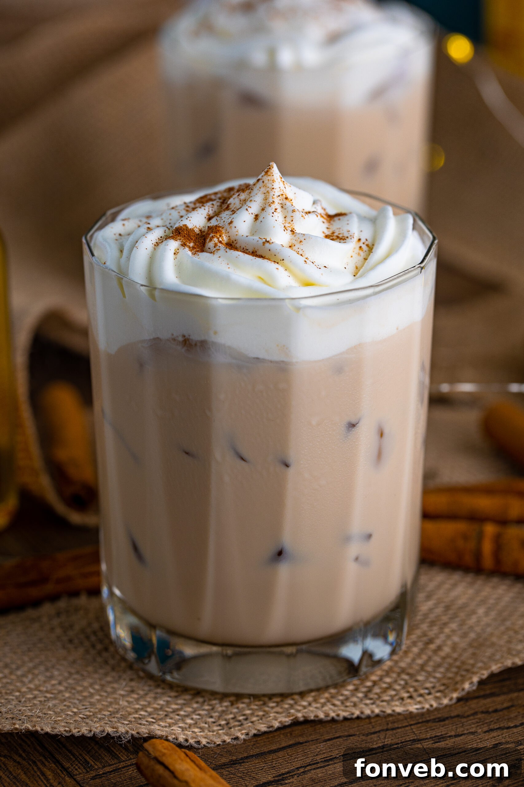 Front view of Cinnamon Roll Cocktail surrounded by cinnamon sticks.