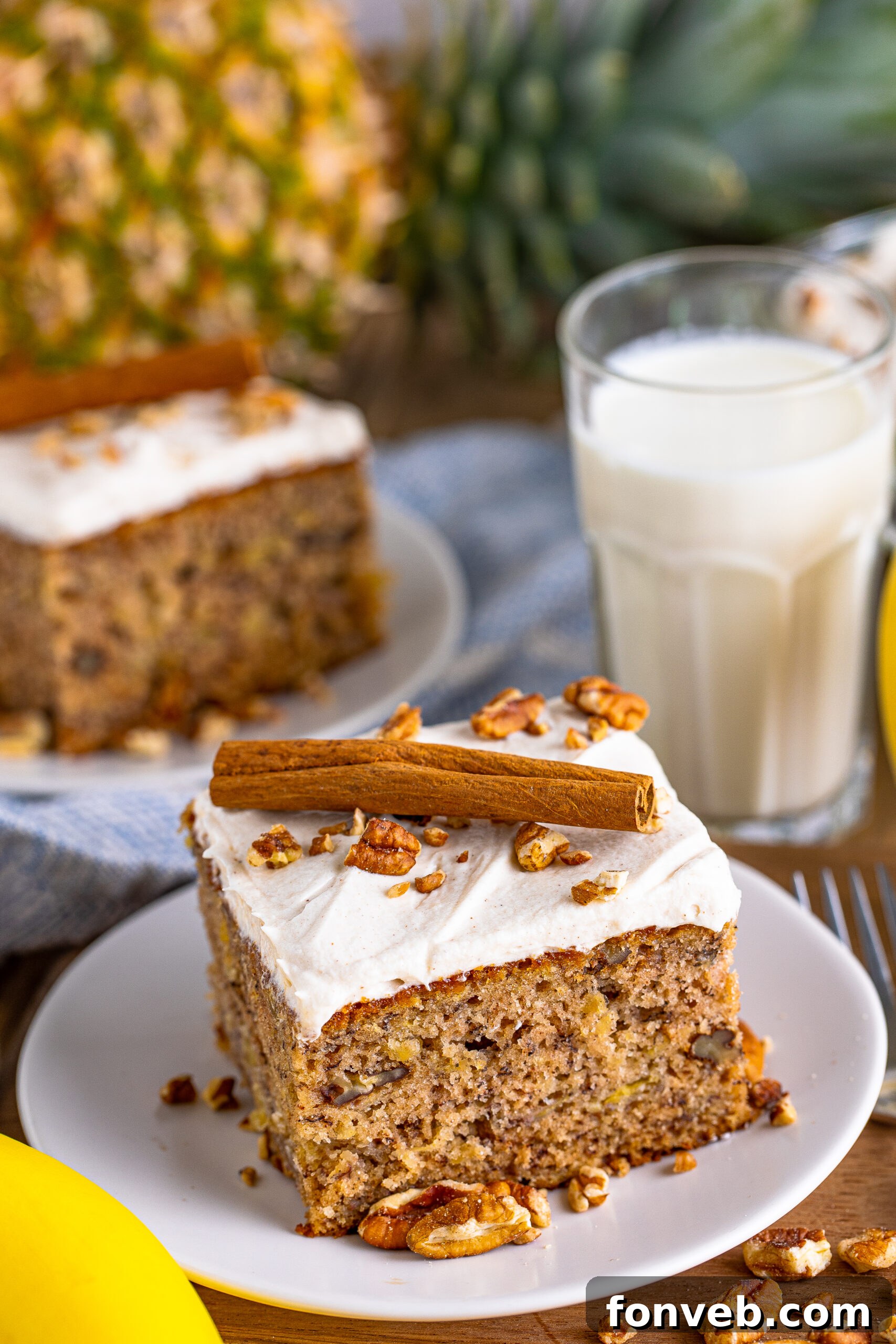 Front view of a beautifully frosted Hummingbird Cake on a white dish, garnished with a cinnamon stick.