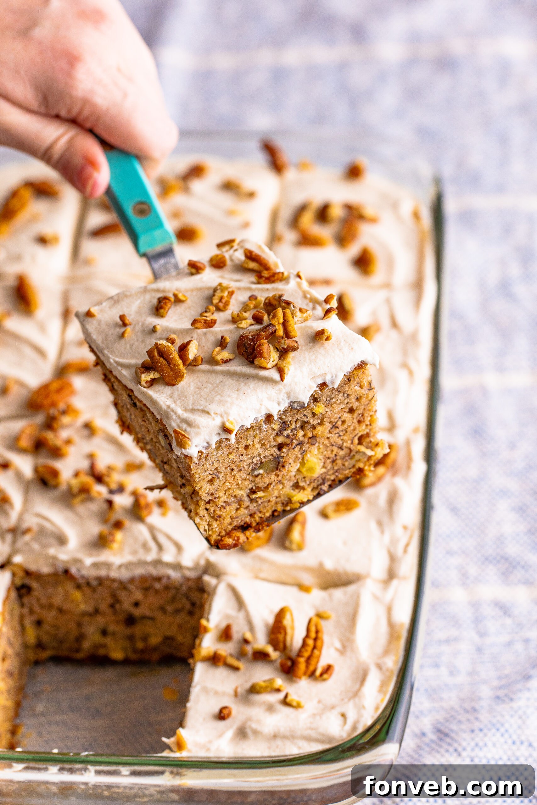 A perfect slice of Hummingbird Cake being lifted from a clear baking dish with a spatula, revealing its moist texture.