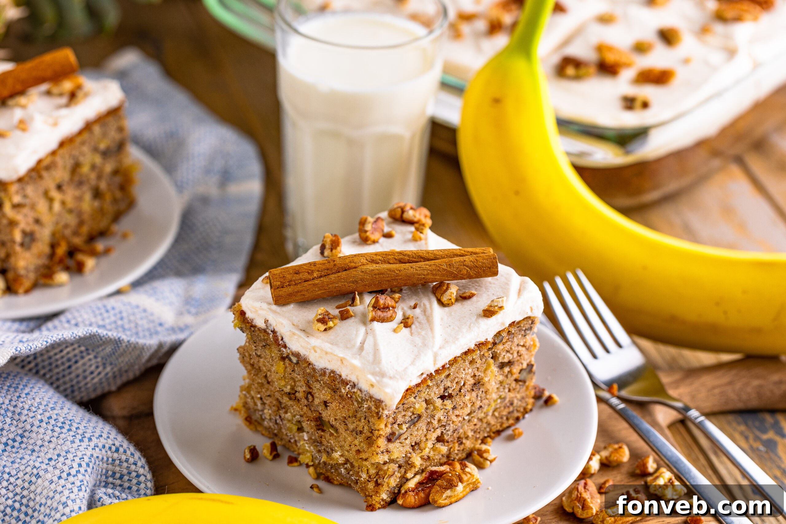 Close-up front view of a slice of Hummingbird Cake, showcasing its moist crumb and rich cream cheese frosting, on a pristine white dish.