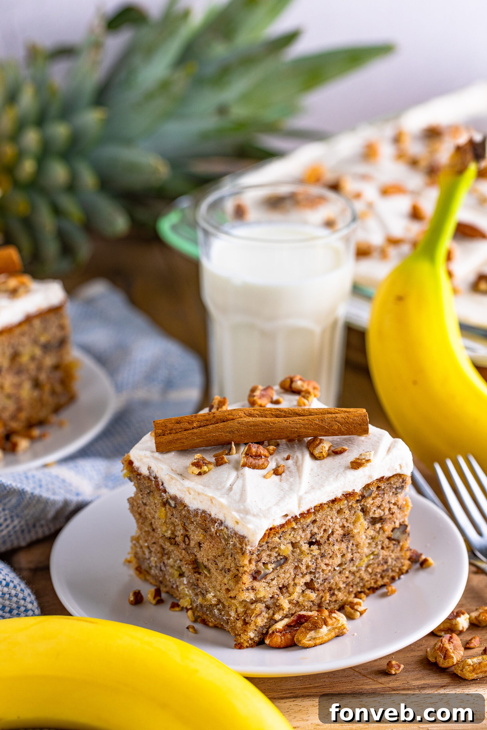 A pristine Hummingbird Cake presented on a white serving plate, beautifully garnished with a single cinnamon stick.
