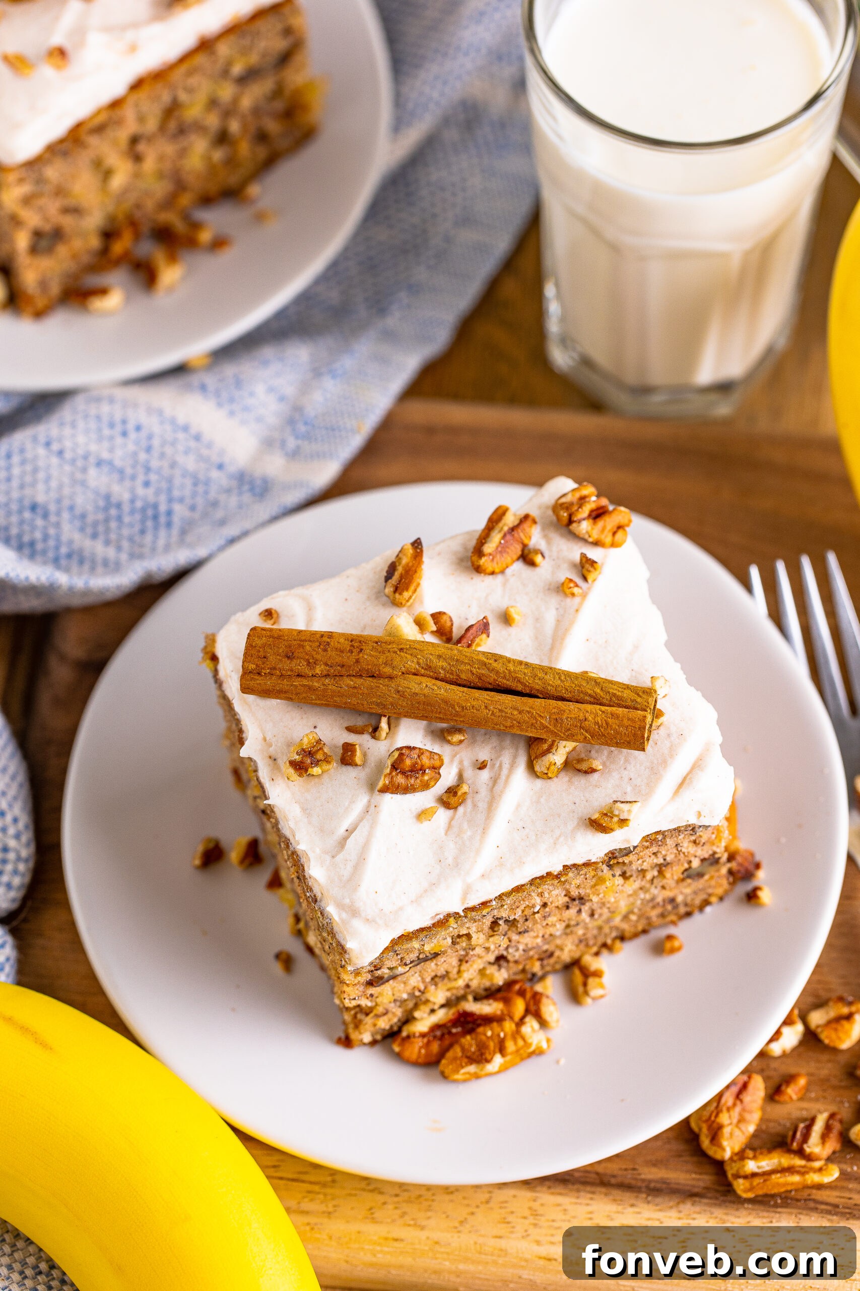 Overhead view of a beautifully presented Hummingbird Cake on a white dish, garnished with a cinnamon stick and a sprinkle of spices.