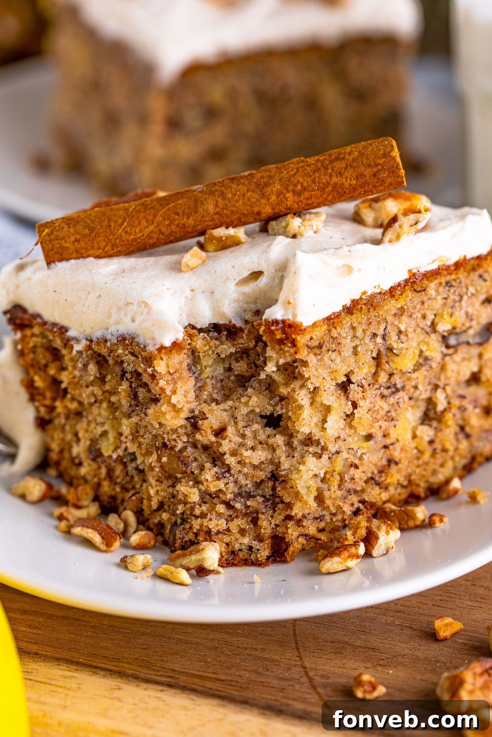 A close-up of a slice of Hummingbird Cake with a bite taken out, showing the intricate layers and the creamy frosting.