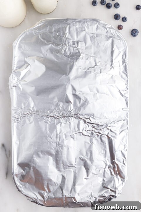 Pouring the egg custard mixture over the bread and blueberries in the baking dish.