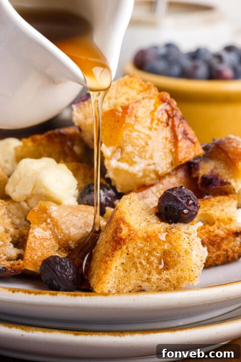 A close-up shot of a small bowl of fresh blueberries and a small jug of maple syrup, perfect accompaniments for French Toast Casserole.