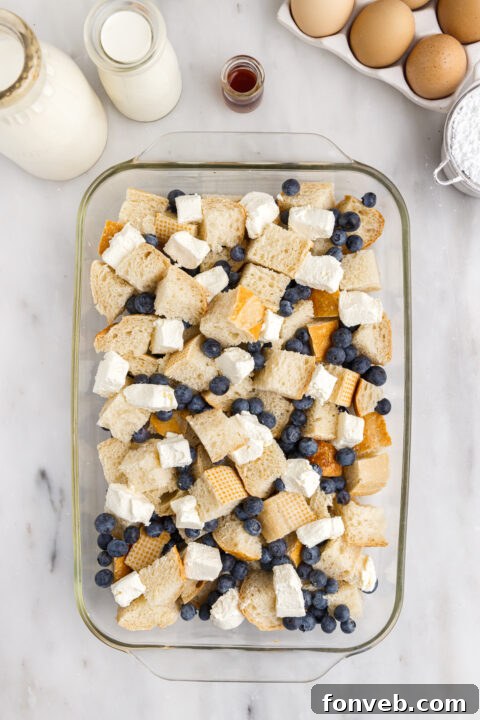 Blueberry French Toast Casserole in a baking dish before baking, showing bread cubes, blueberries, and cream cheese.