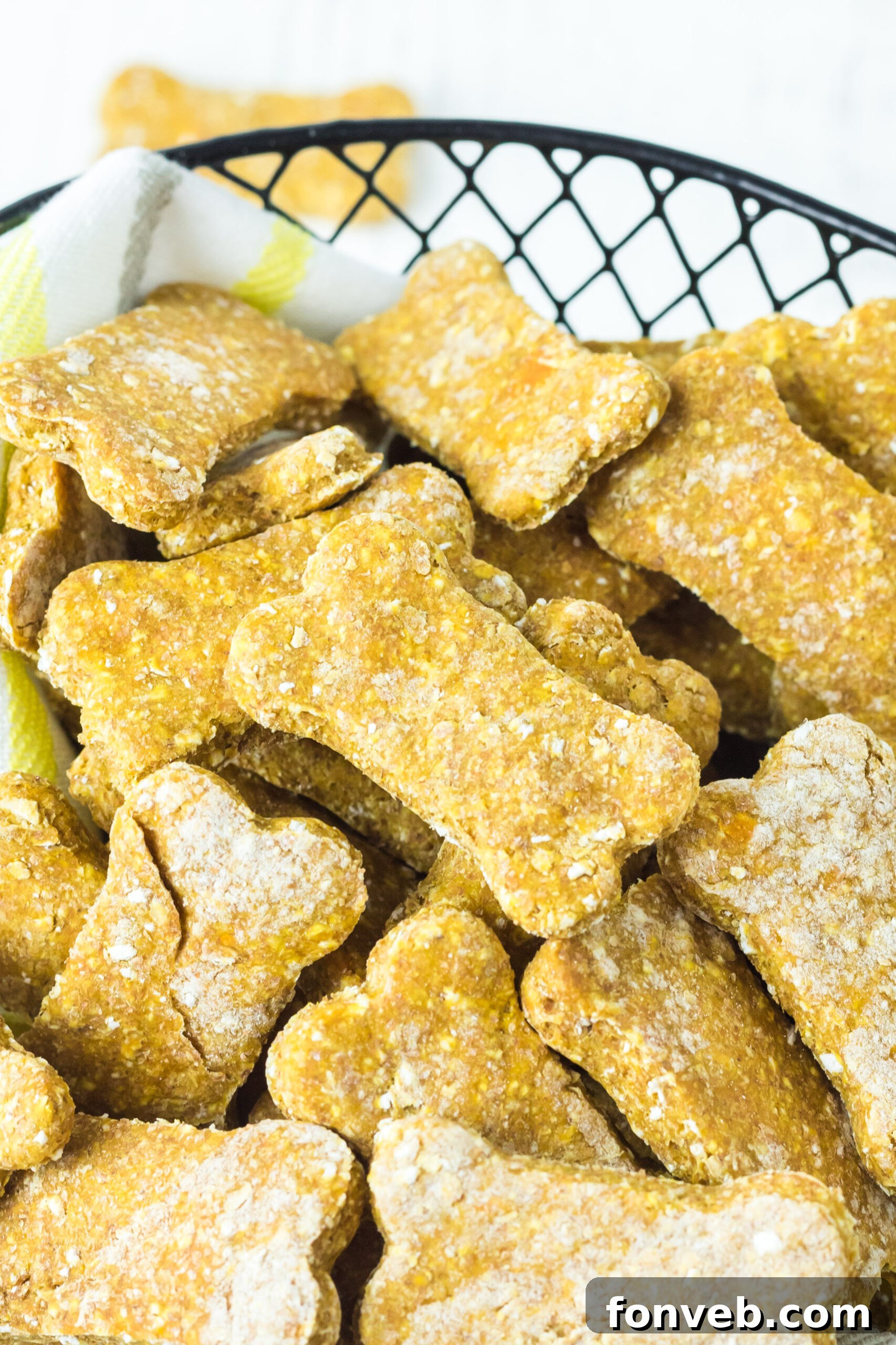 Close-up view of freshly baked Sweet Potato and Pumpkin Dog Treats in a rustic wire basket lined with soft linen, highlighting their golden texture and enticing aroma.