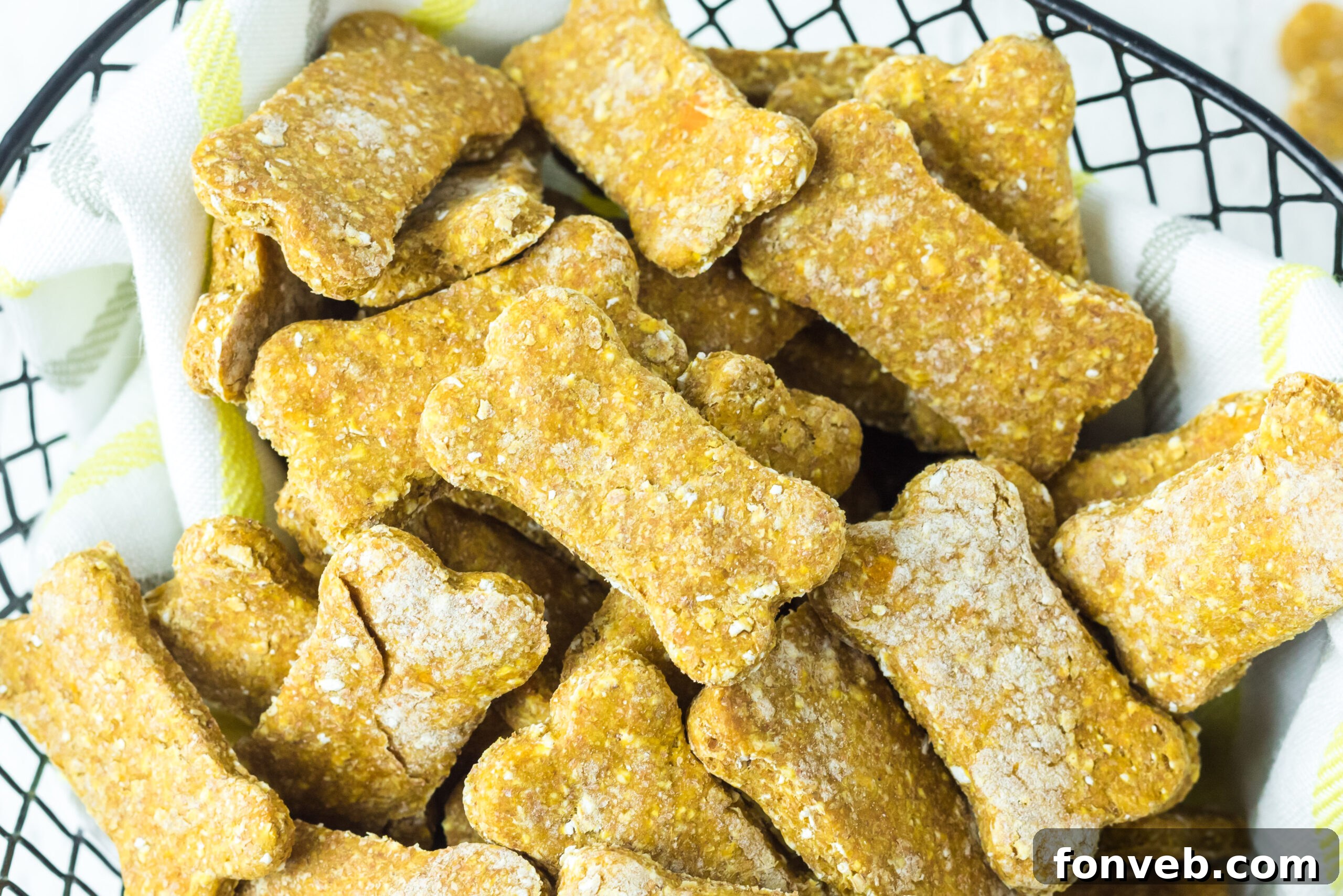 Overhead perspective of homemade Sweet Potato and Pumpkin Dog Treats arranged neatly in a wire basket with a linen lining, showcasing their uniform shapes and inviting appearance.