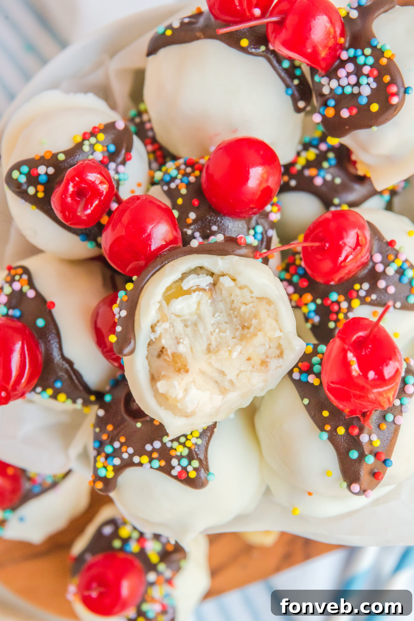 An intimate view of Banana Split Truffles stacked high in a dish, with one truffle having a delicate bite removed, revealing its creamy, flavorful interior.