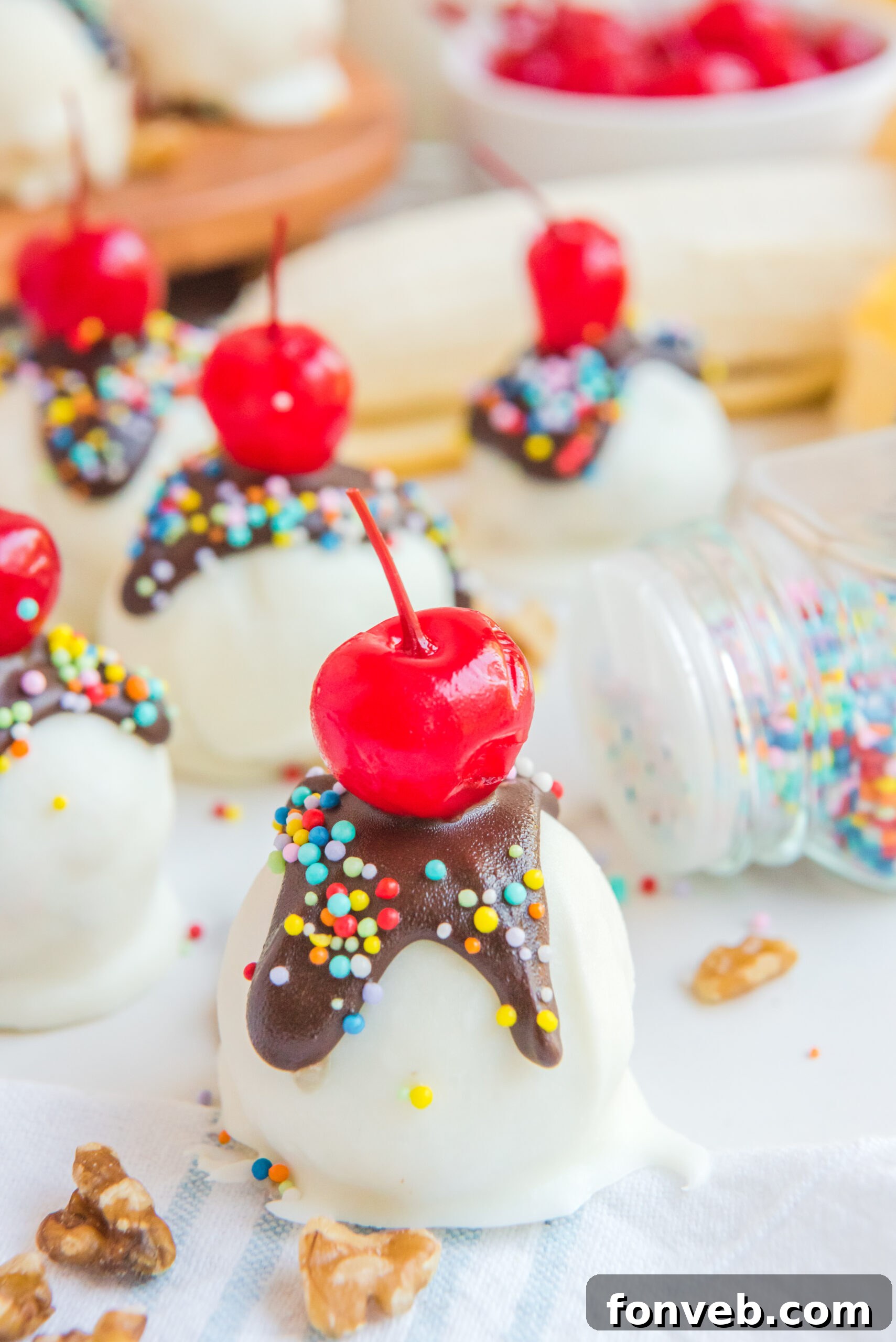 Banana Split Truffles elegantly presented, adorned with vibrant rainbow sprinkles and a scattering of chopped nuts, showcasing their festive and inviting appearance.