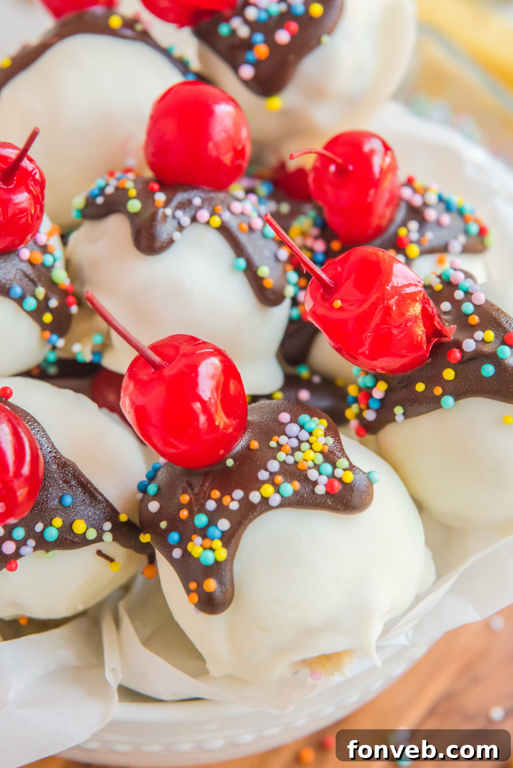 An extremely close-up view of a Banana Split Truffle in a white bowl, highlighting its smooth, glossy finish and the enticing texture of its coating.