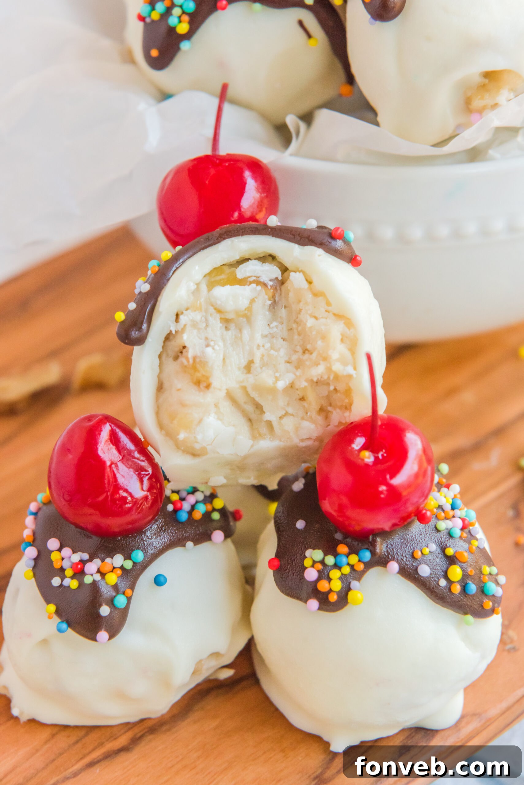 A close-up shot of Banana Split Truffles, with the top truffle exhibiting a perfect bite, revealing the tender, creamy interior against the smooth chocolate exterior.