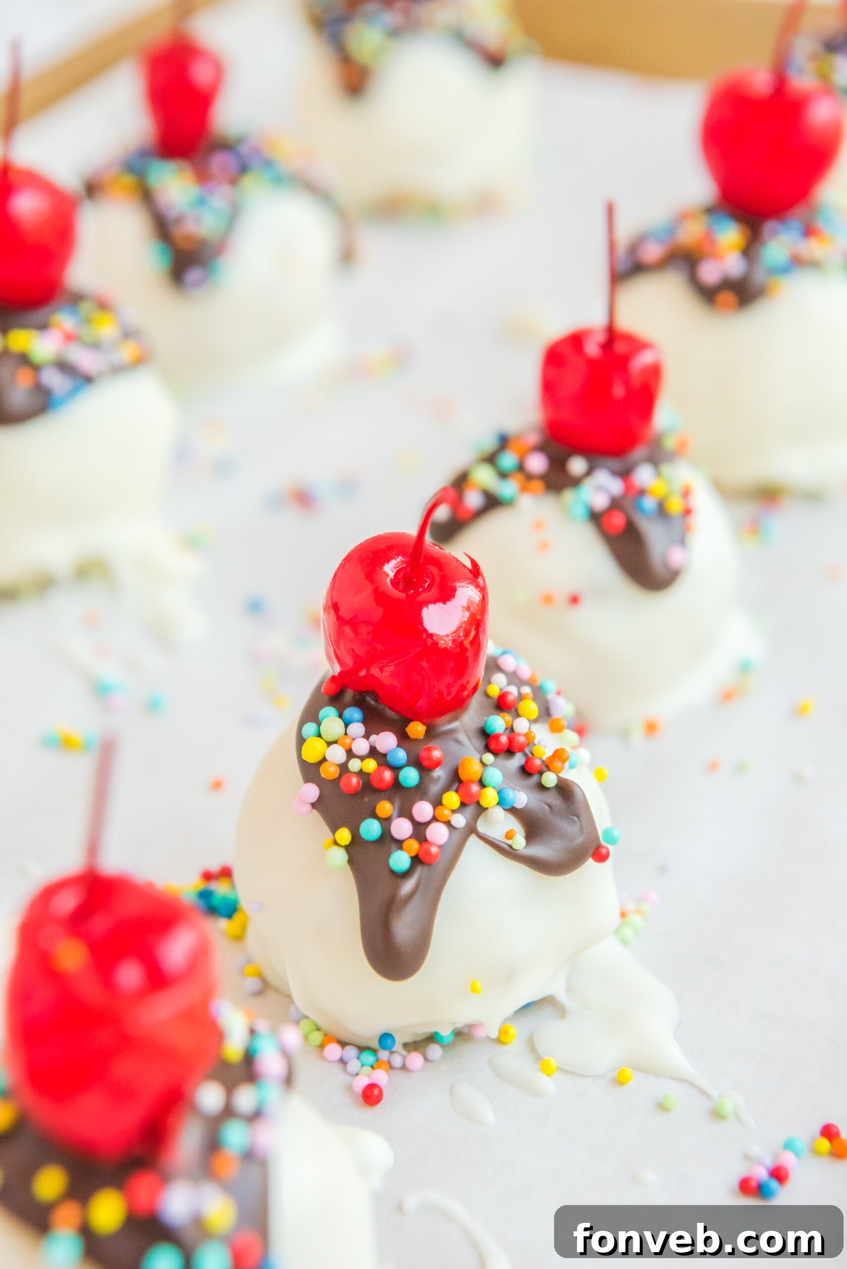A close-up view of freshly made Banana Split Truffles resting on a sheet of parchment paper, highlighting their textured surface and vibrant toppings.