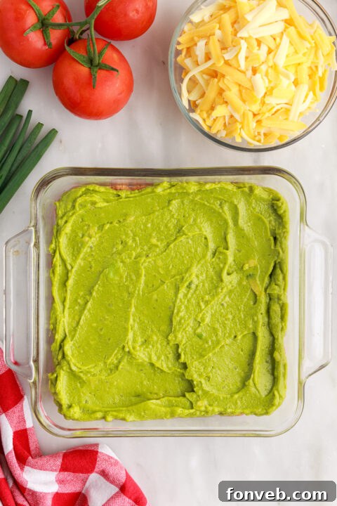 Step 4: Generously sprinkling shredded Mexican cheese blend over the sour cream layer.