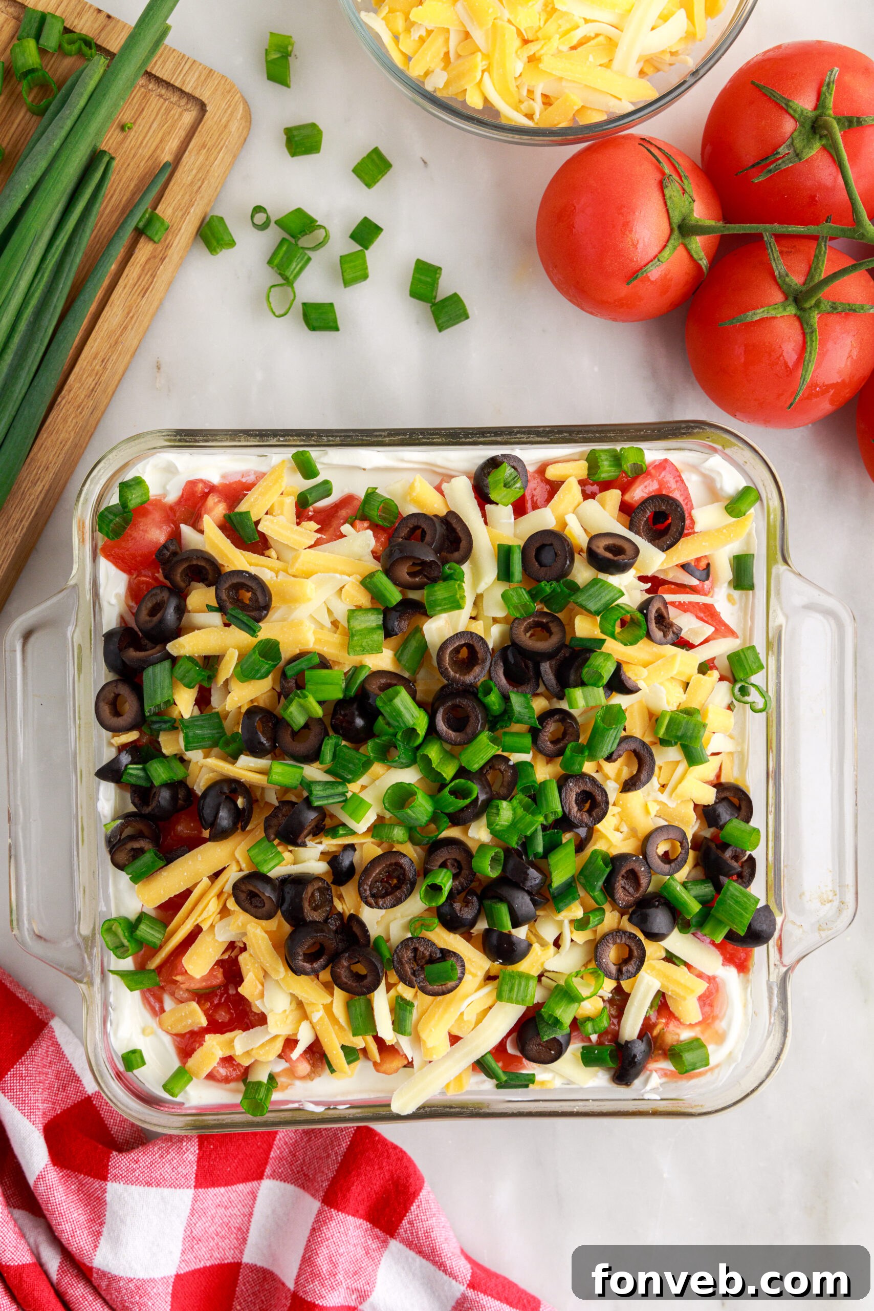 An overhead view of the freshly prepared 7-Layer Dip, perfectly arranged in a clear rectangular baking dish, ready for serving.