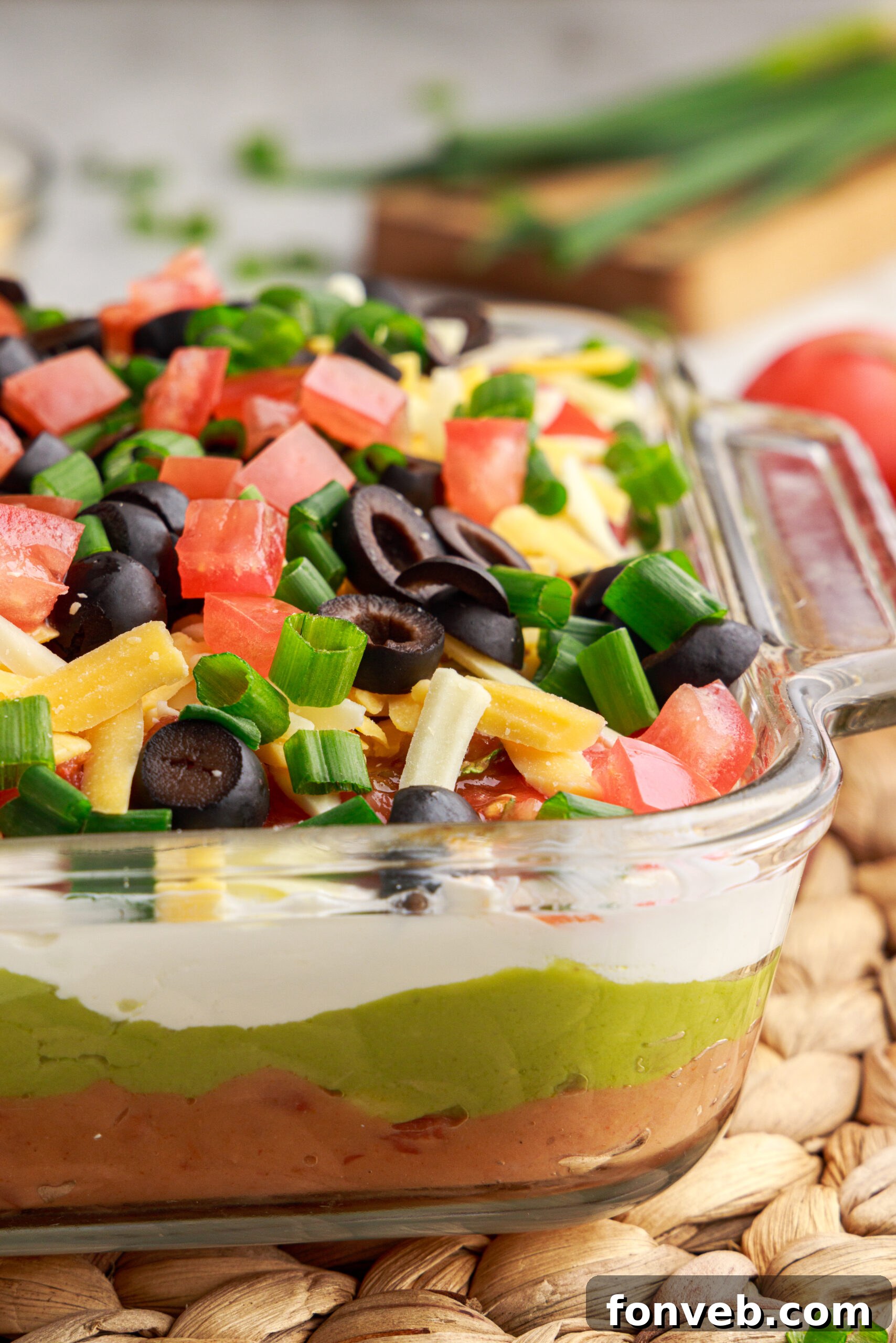 A close-up view of the tempting 7-Layer Dip in a clear baking dish, highlighting the vibrant colors and appealing textures of each individual layer.