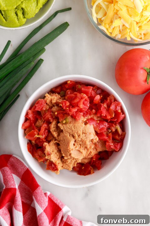 Step 1: Spreading a layer of refried beans mixed with Rotel into the bottom of a clear baking dish.