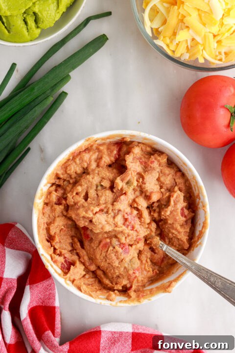 Step 2: Spreading a smooth, even layer of fresh guacamole over the seasoned refried bean base.