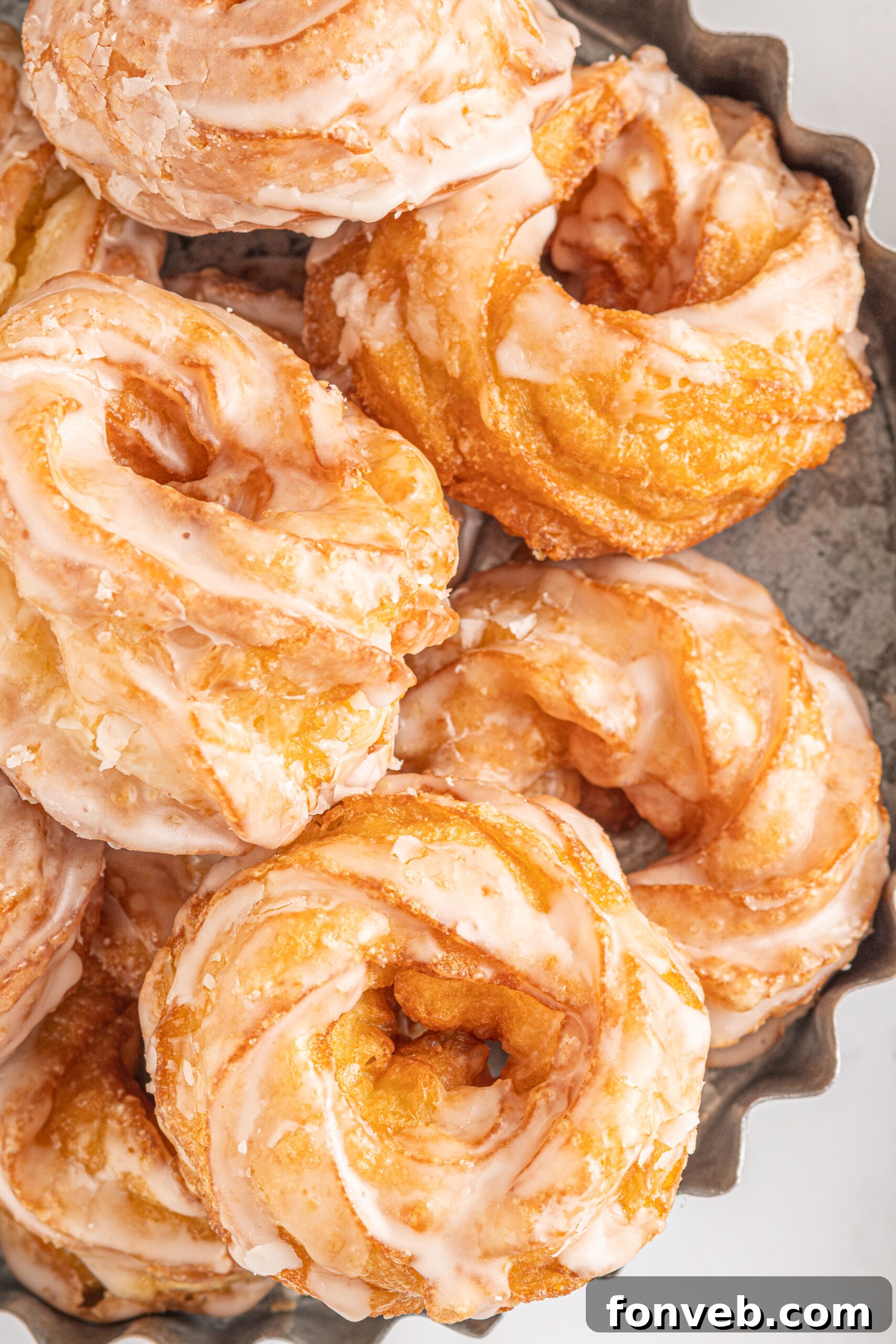 Up close view of French Crullers stacked on a silver serving tray.