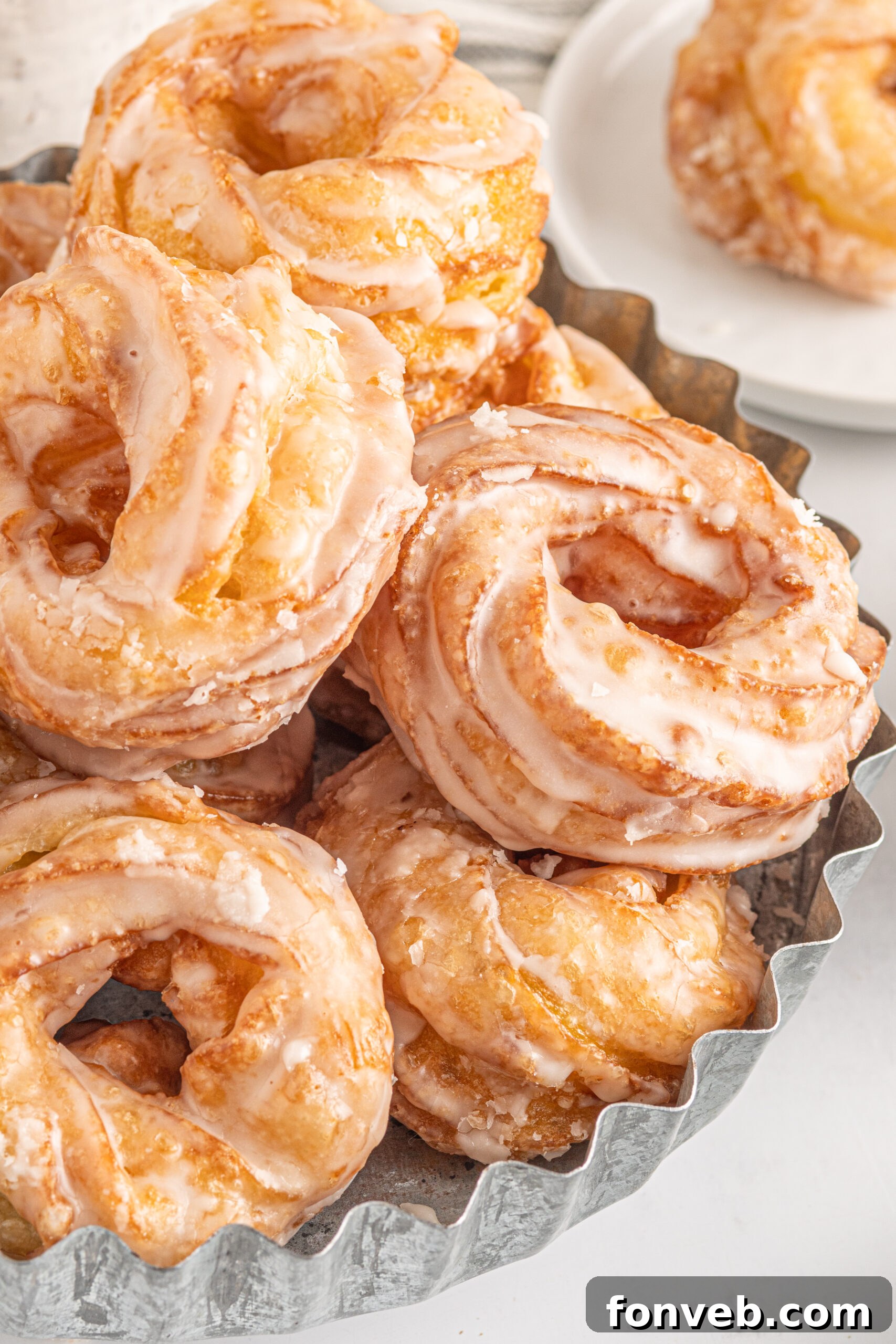 Up close view of French Crullers stacked on a silver serving tray.
